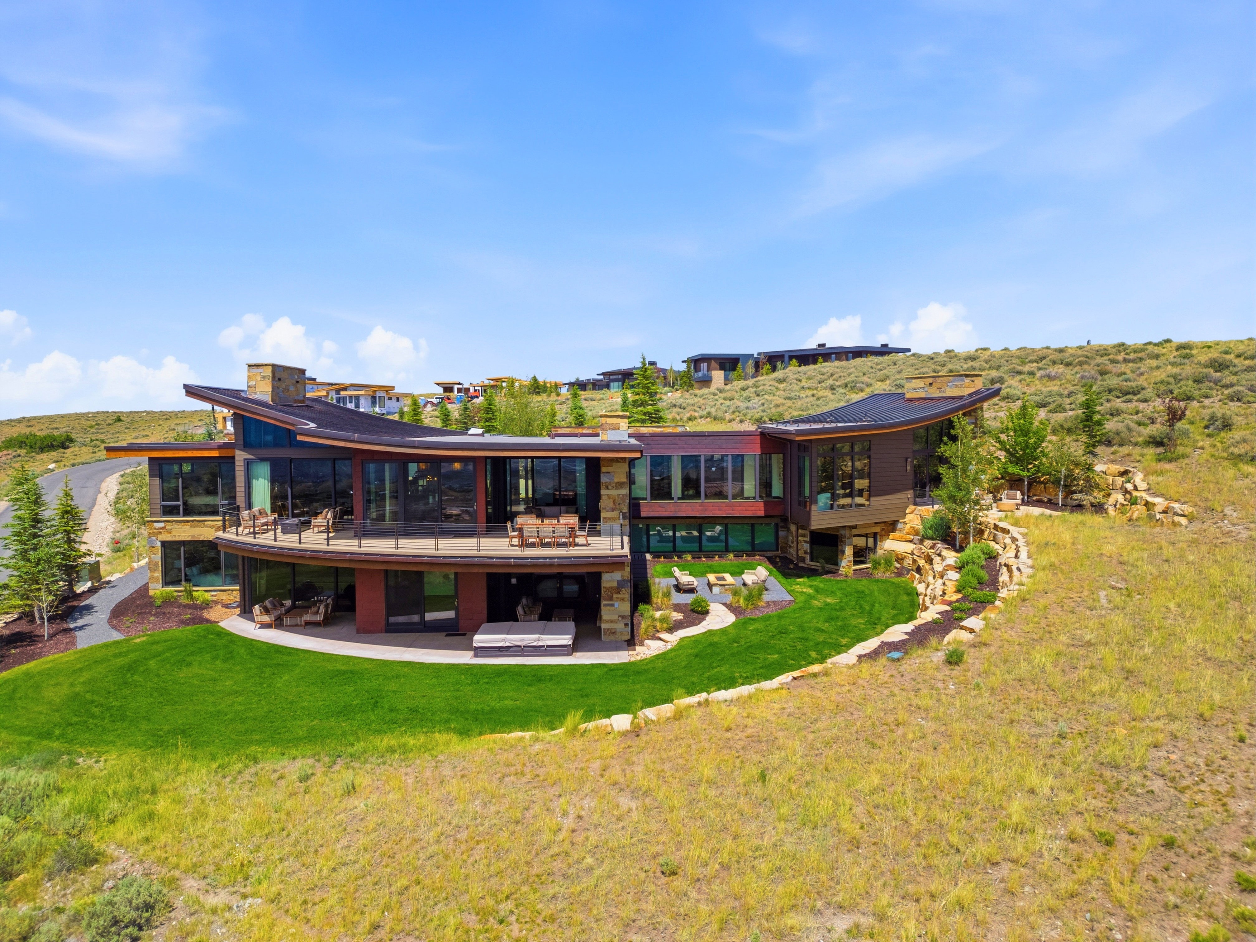 Contemporary architectural design featuring extensive glazing, stone accents, and curved rooflines