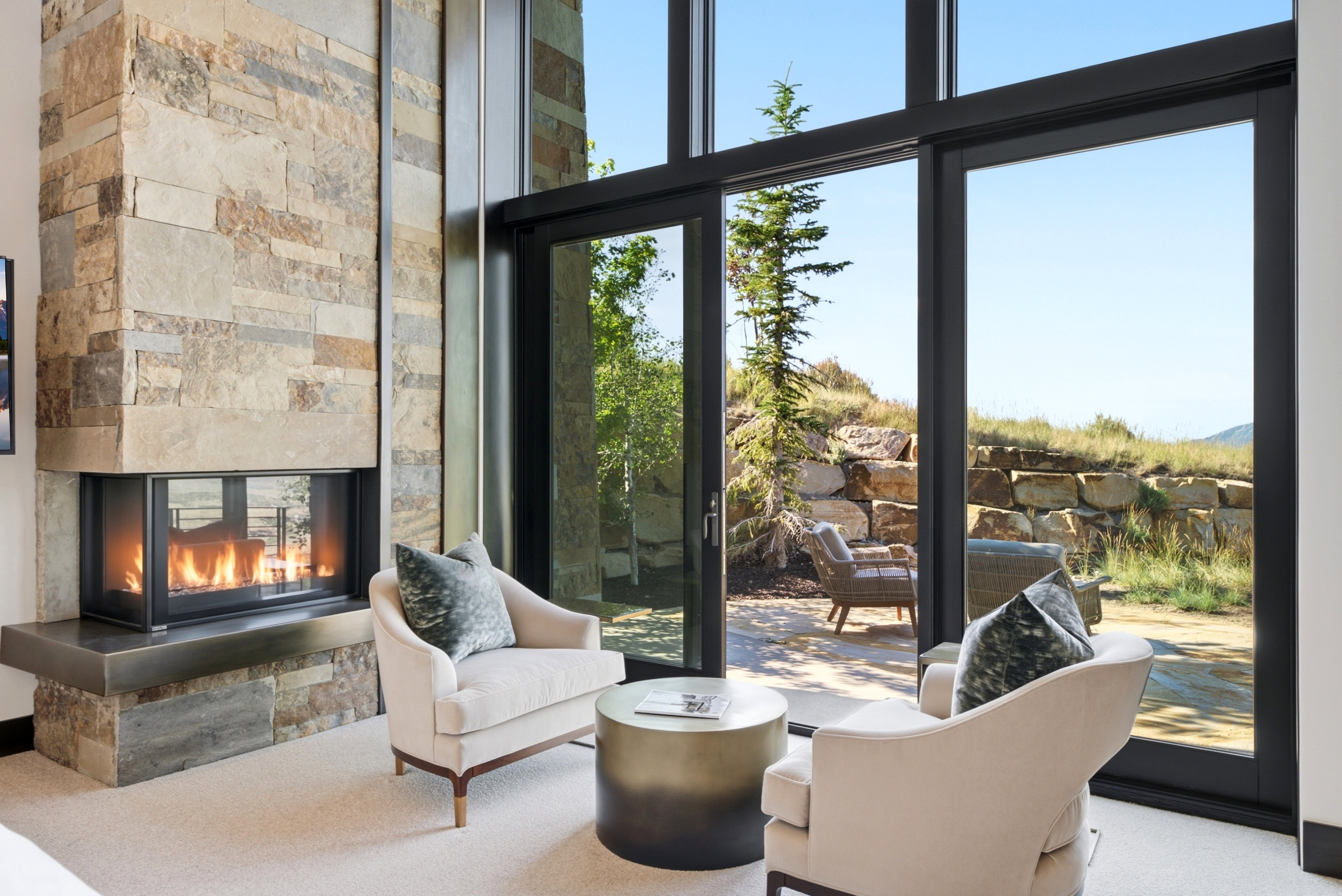 Floor-to-ceiling windows with direct access to an outdoor patio featuring a stone retaining wall