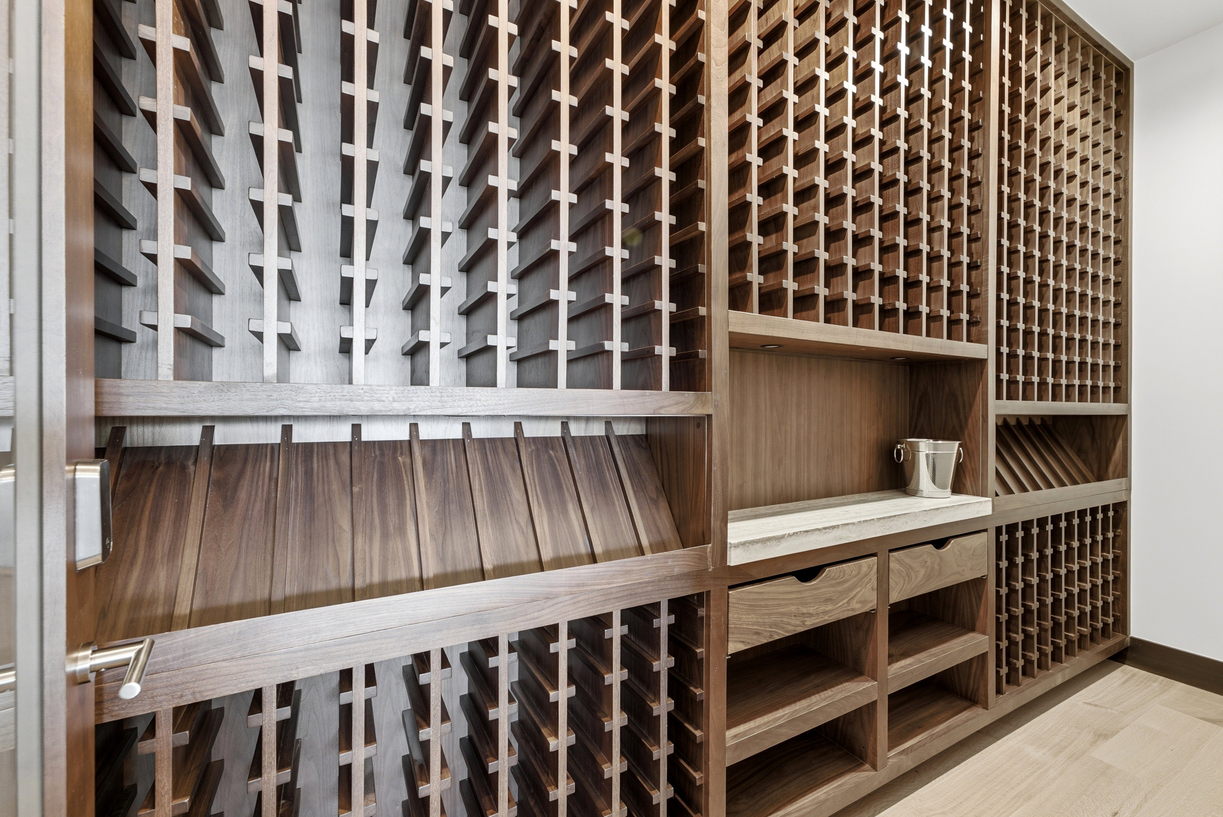 Custom wood wine cellar featuring extensive bottle storage, a light-toned countertop, and integrated drawers