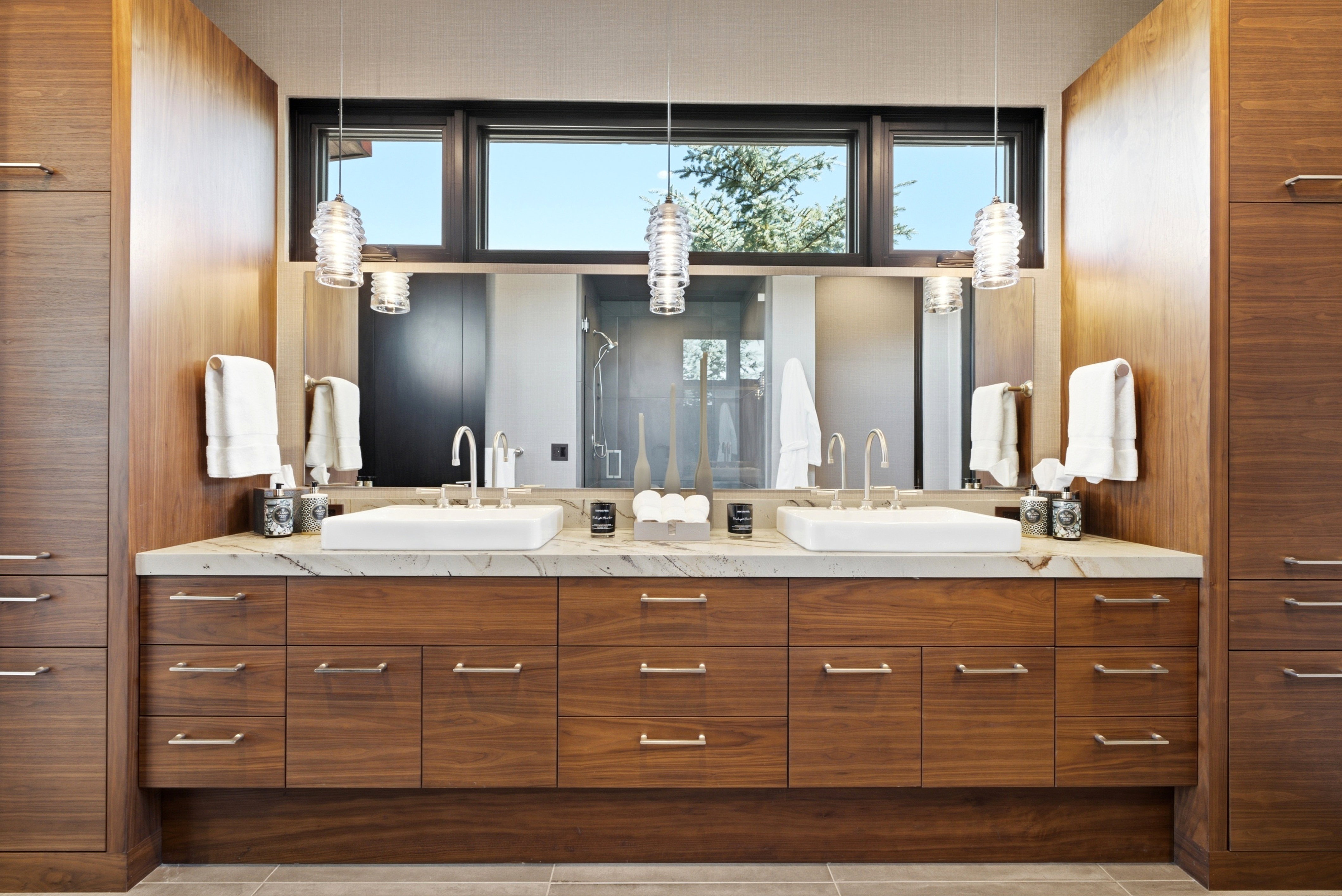 Dual vessel sinks set on a light-toned countertop with integrated mirrors