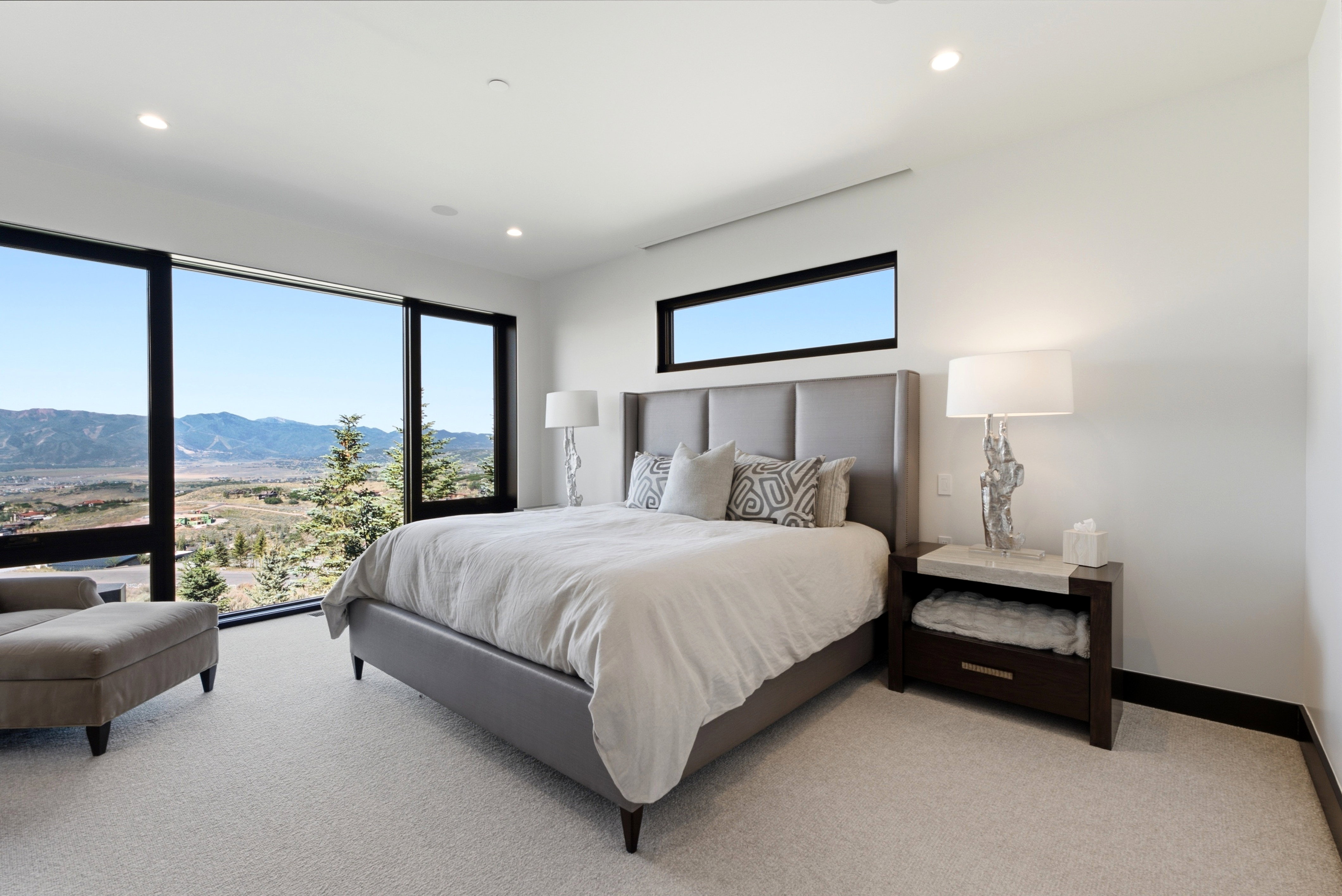 Spacious bedroom featuring floor-to-ceiling windows, recessed lighting, white walls, and light-colored carpeting
