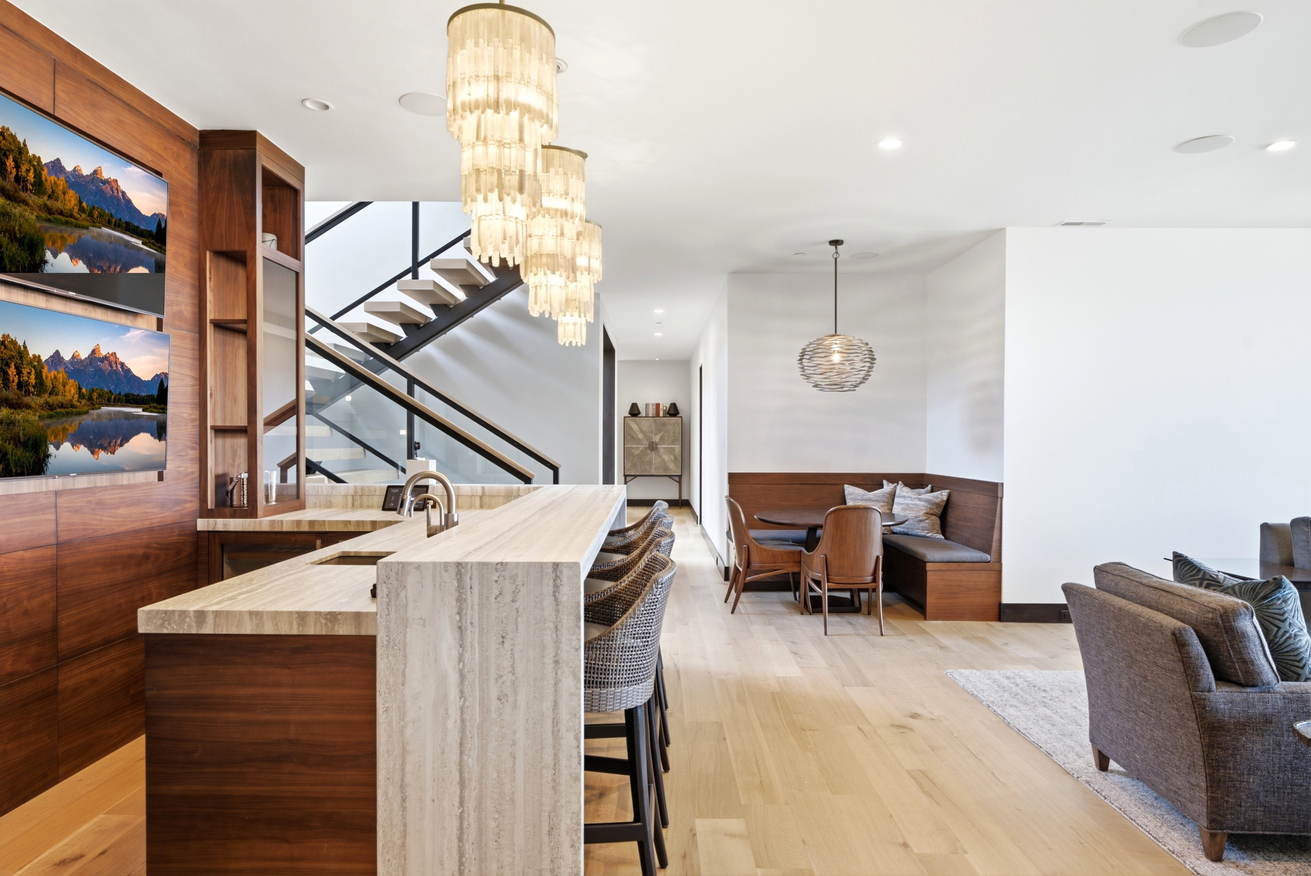 Custom wet bar with a stone countertop and waterfall edge, integrated cabinetry, and dual display screens