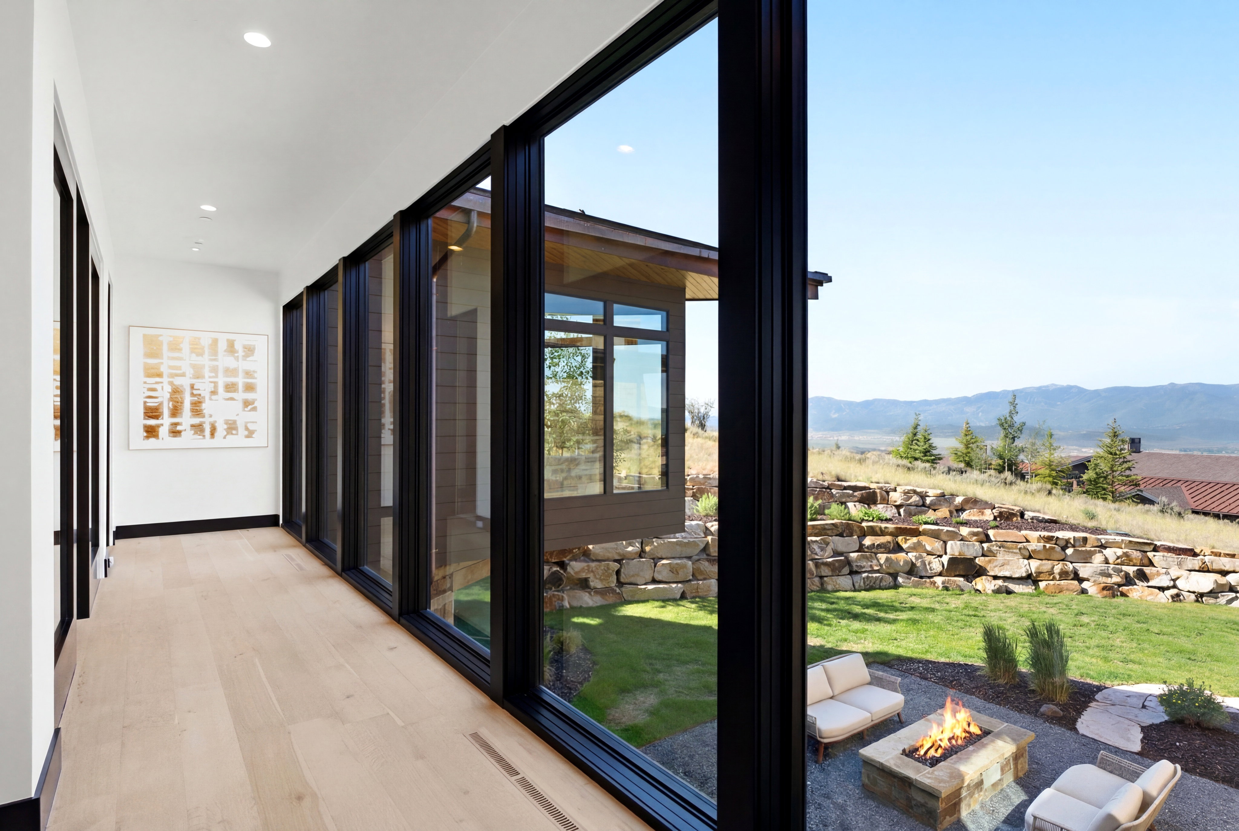 Interior walkway featuring a wall of floor-to-ceiling windows, light wood-finish flooring, and recessed ceiling lighting