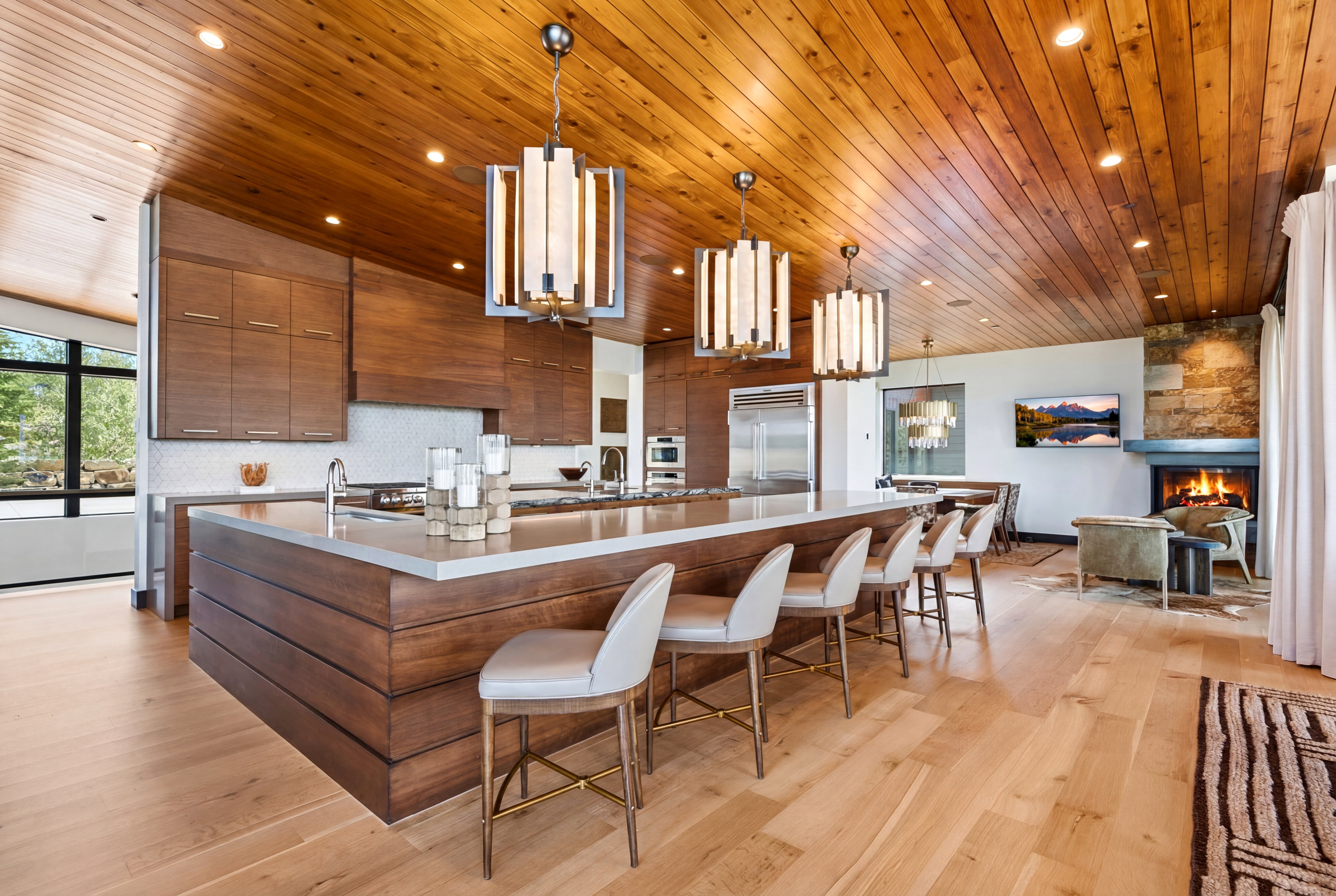 Gourmet kitchen featuring a large island with seating, stainless steel appliances, and wood-finish cabinetry, complemented by a wood-paneled ceiling and light wood-finish flooring