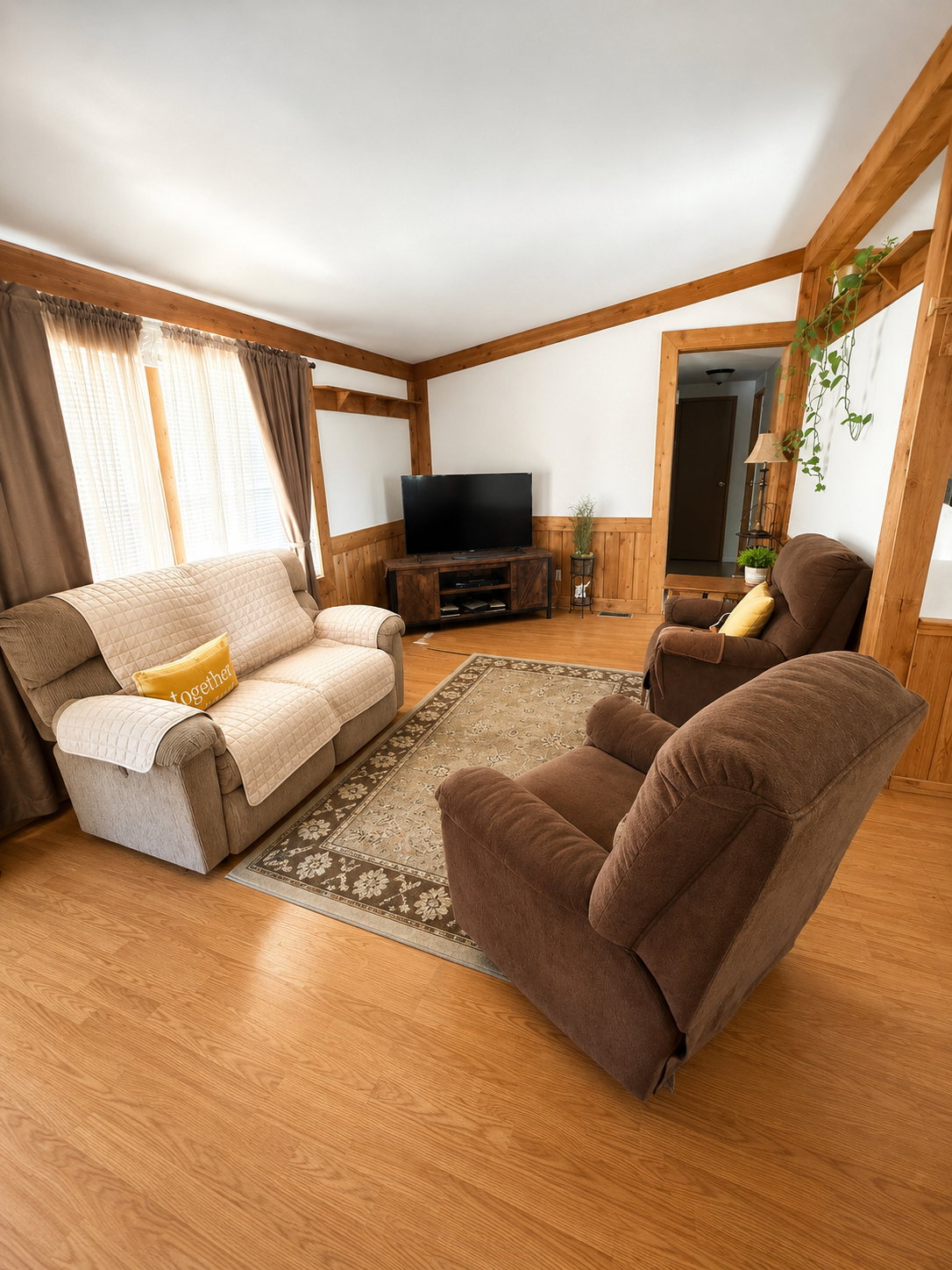 Living area featuring wood-finish flooring, exposed wood beams, and wainscoting