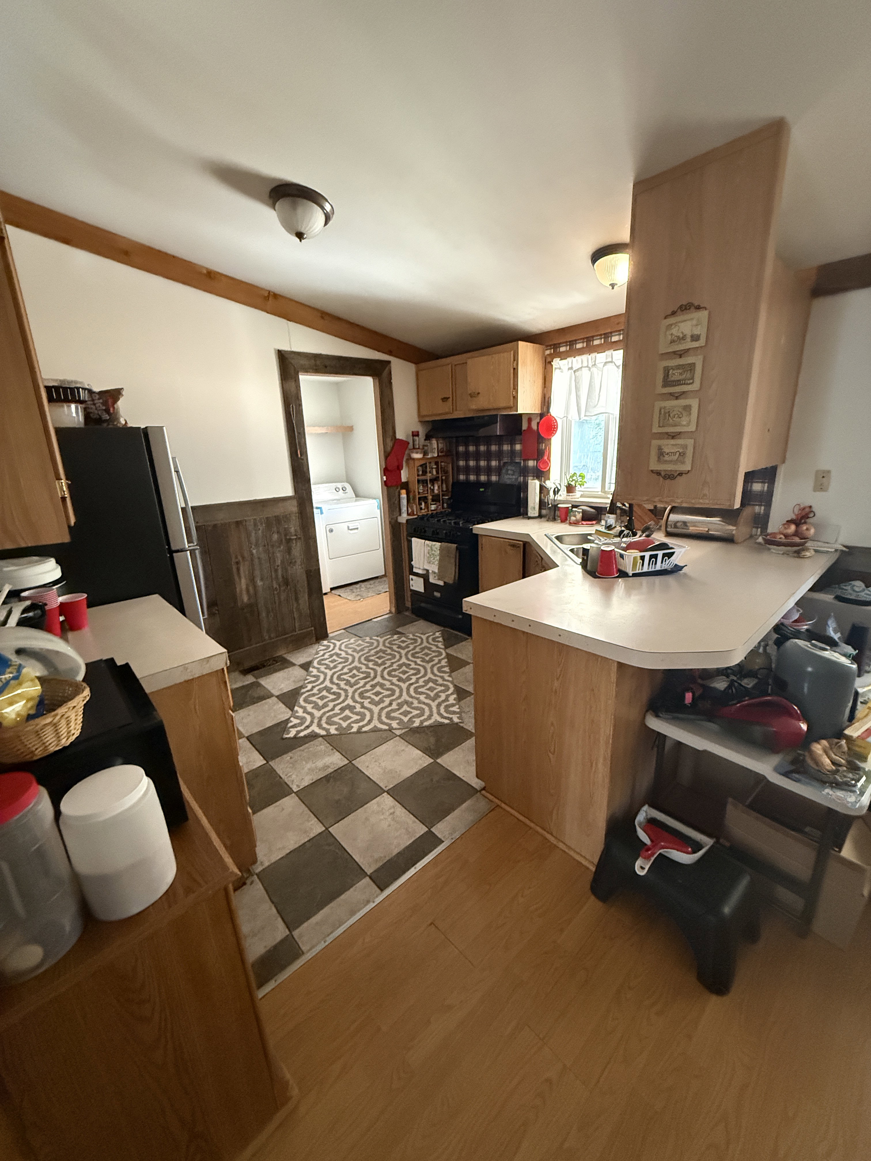 Kitchen featuring wood-finish cabinetry and countertops, black appliances, a checkerboard tile floor, and wood-finish flooring