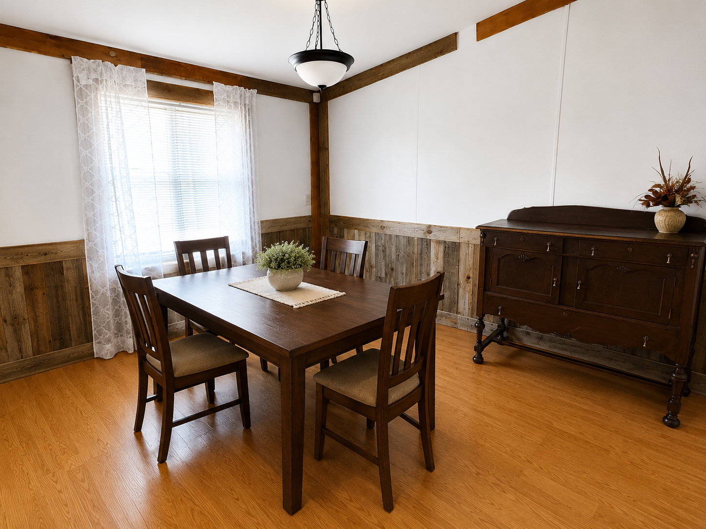 Dining area featuring wood-finish flooring, half-wall wood paneling, white walls, and exposed ceiling beams