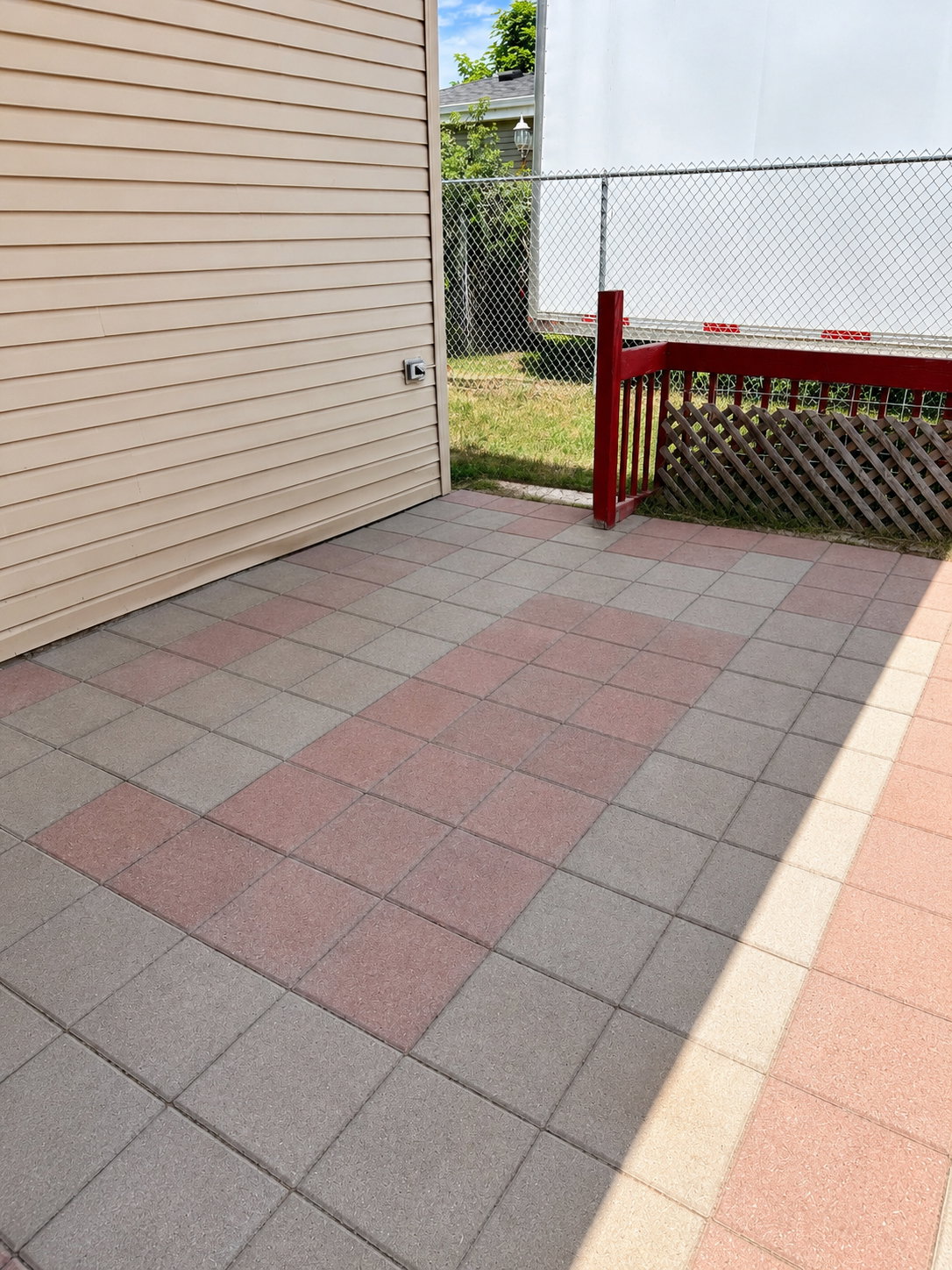 Paved patio area featuring a red and gray tile pattern