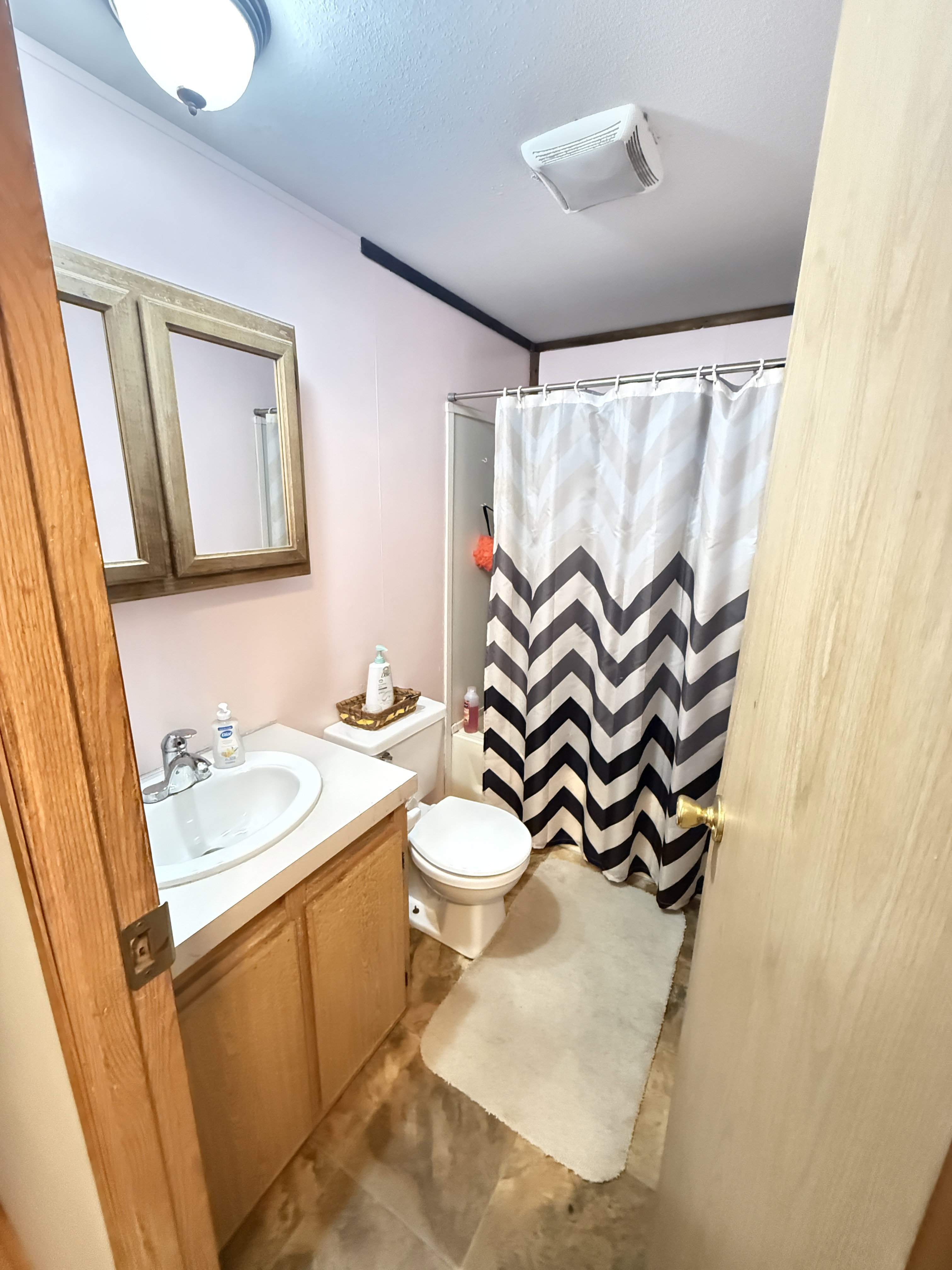 Bathroom featuring a single vanity with laminate countertop, built-in medicine cabinet, and a full shower enclosure