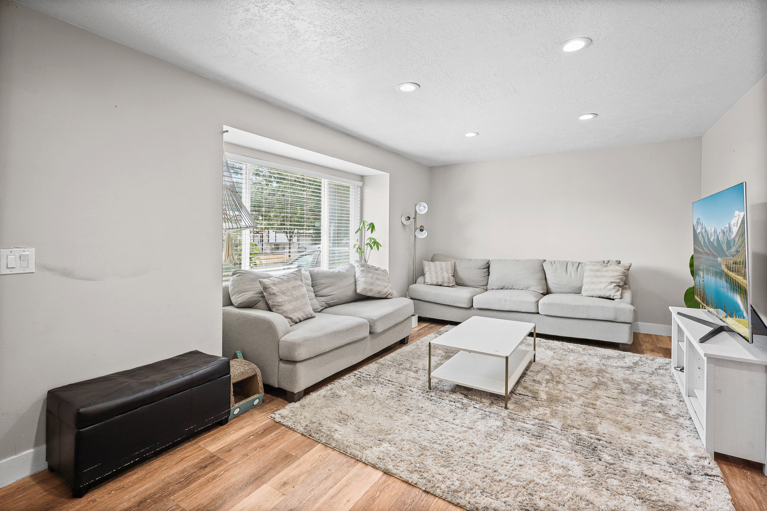 Living area featuring wood-finish flooring, recessed lighting, and a prominent bay window