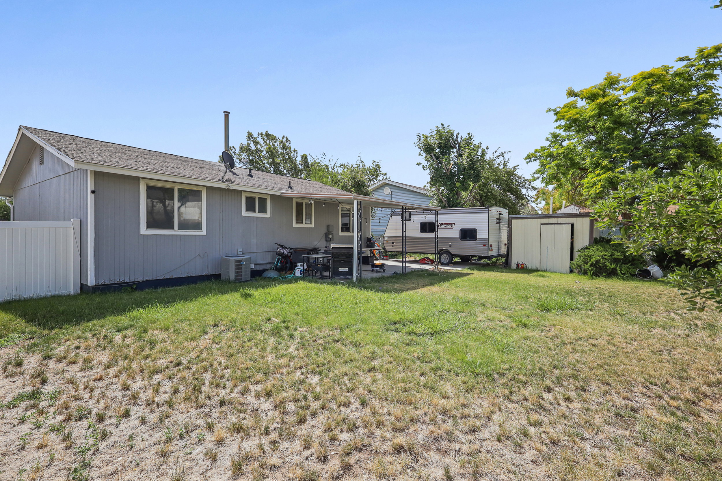 Rear exterior featuring a covered patio, multiple windows, and a fenced perimeter