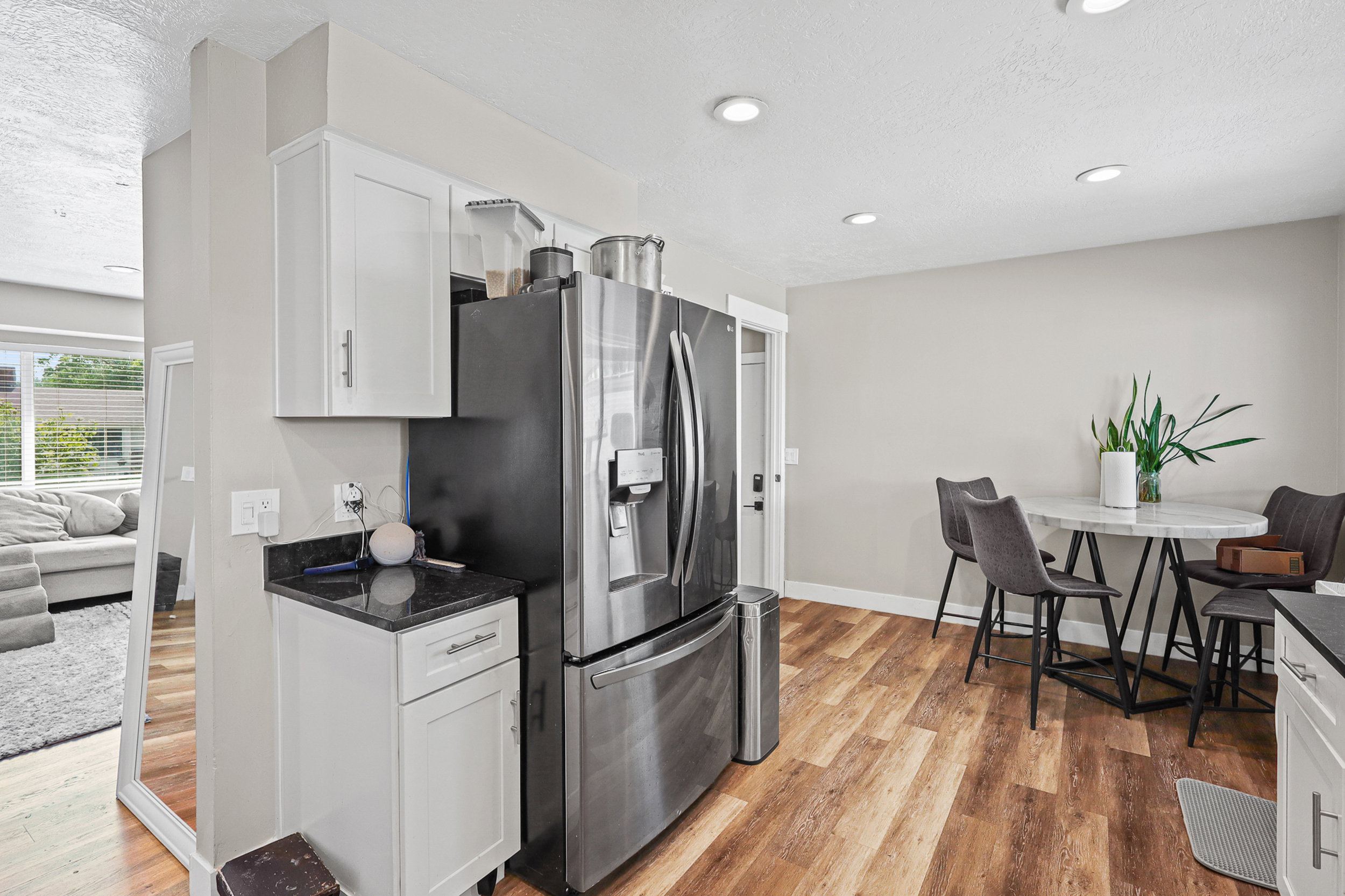 Kitchen area featuring stainless steel appliances, white cabinetry, dark countertops, and wood-finish flooring
