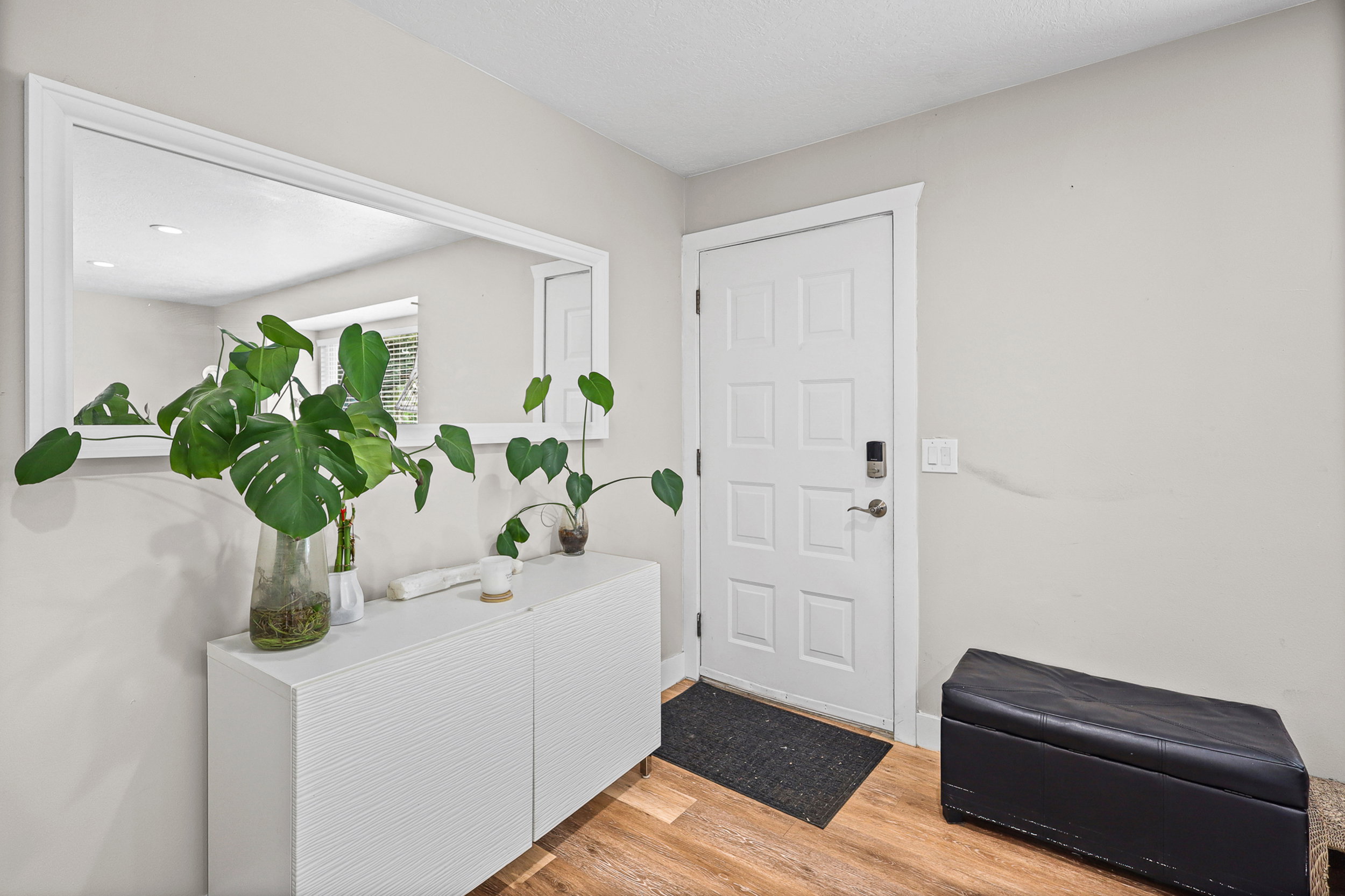 Entryway featuring wood-finish flooring, a white paneled door with smart lock hardware, and light neutral wall paint