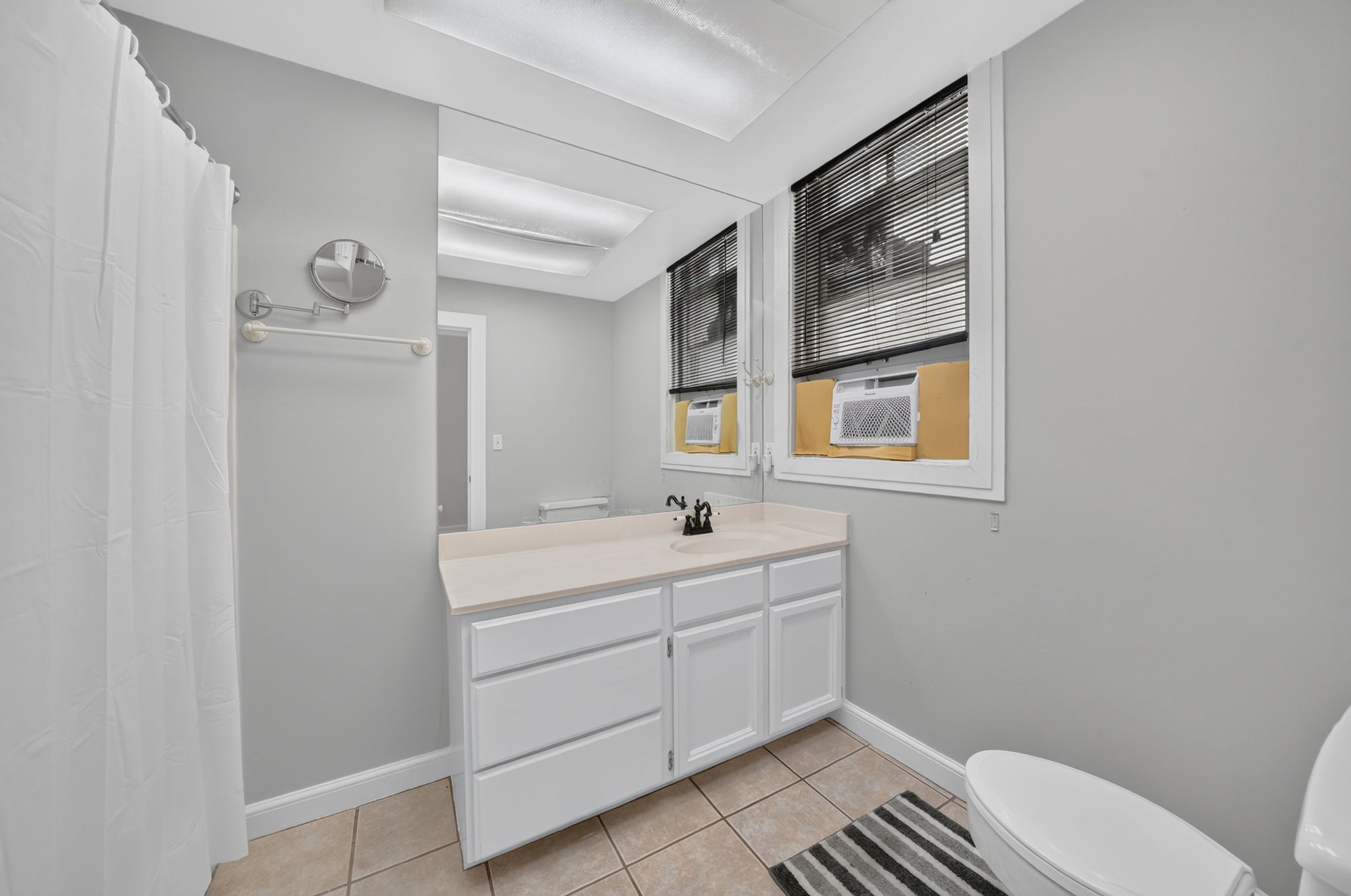 Bathroom featuring a vanity with white cabinetry, a light-toned countertop, and a built-in sink with a dark-finish faucet