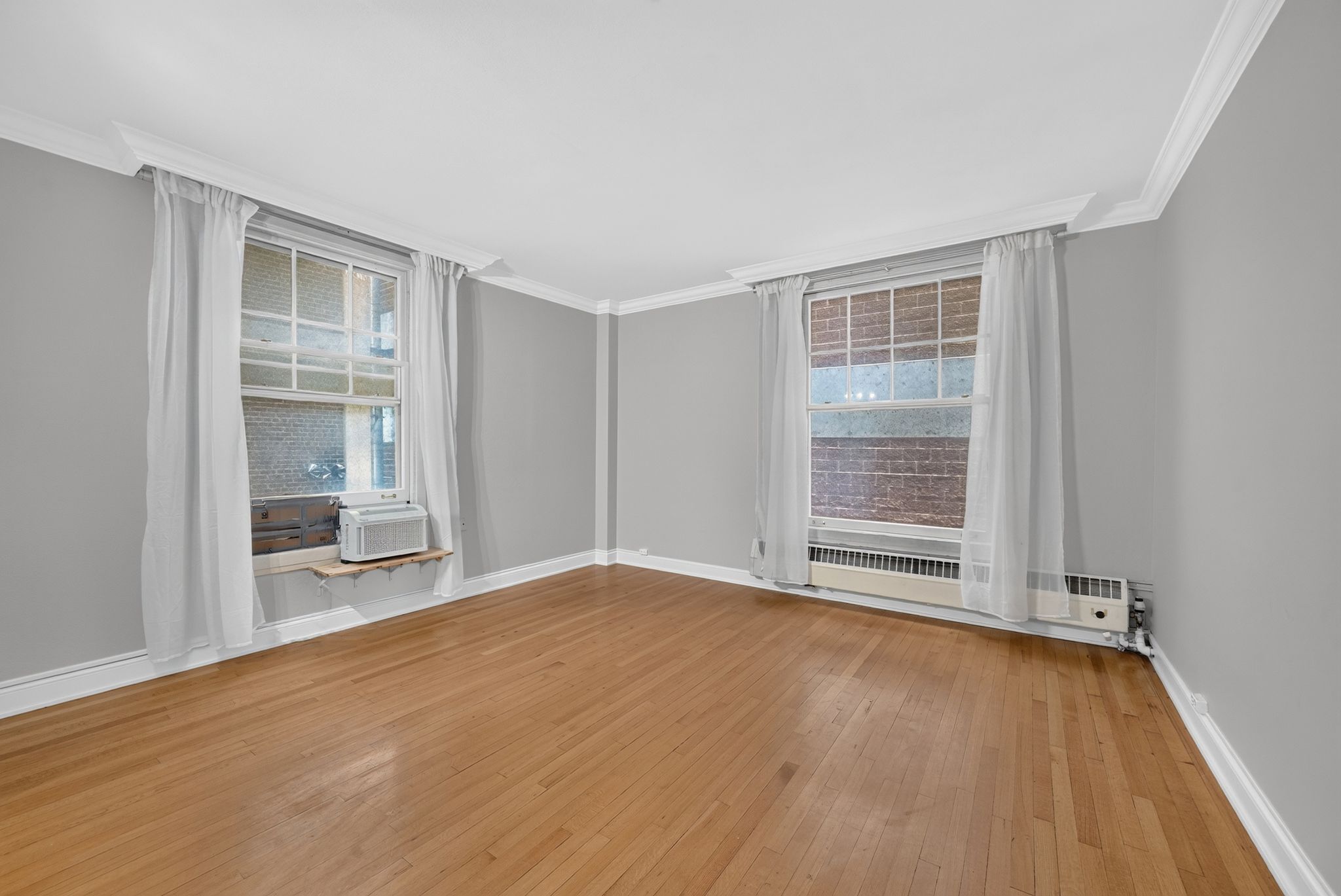 Hardwood flooring complementing light gray walls and white crown molding