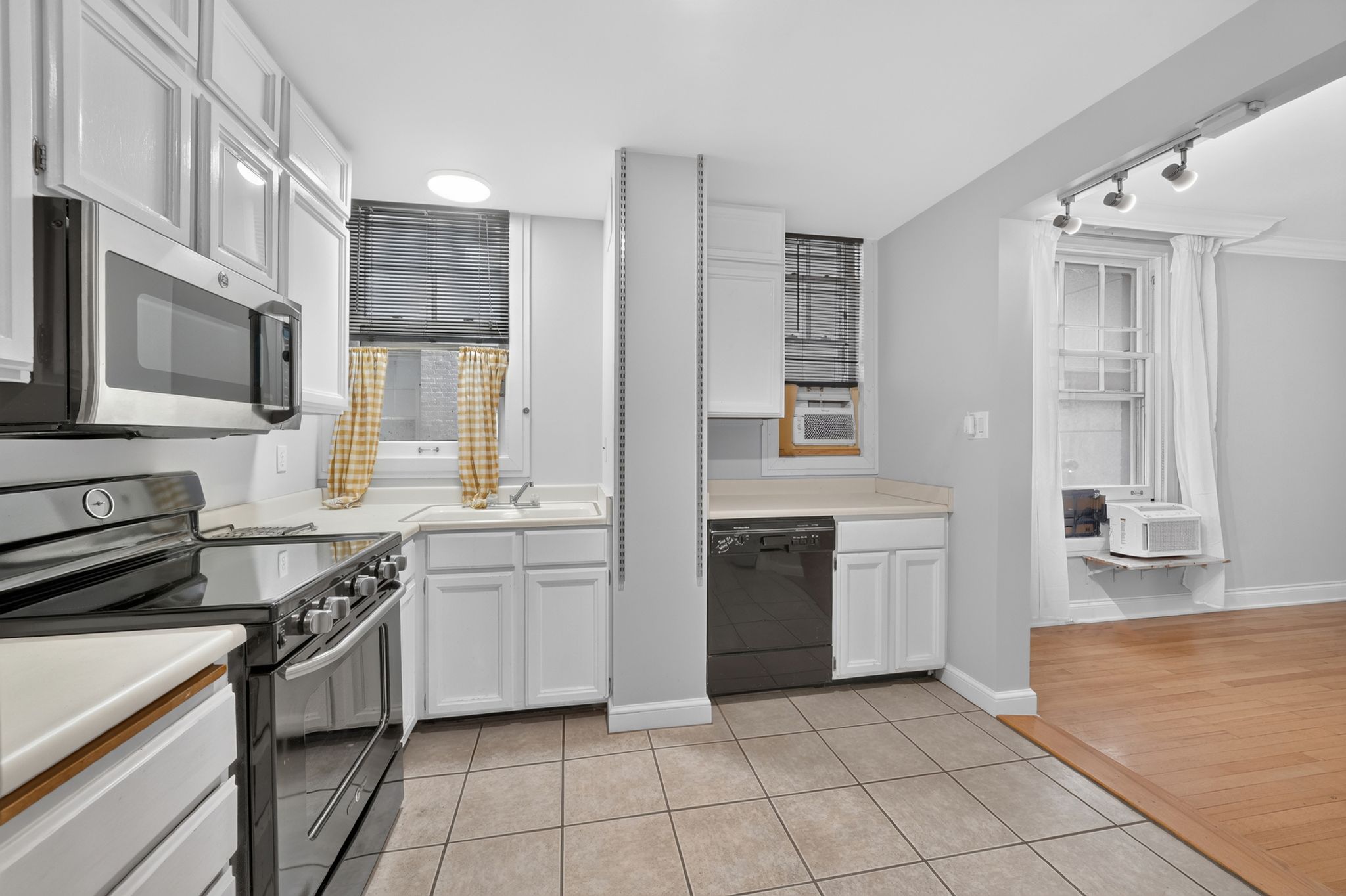 Kitchen featuring white cabinetry, a stainless steel microwave, a black range with a smooth cooktop, a black dishwasher, and tiled flooring