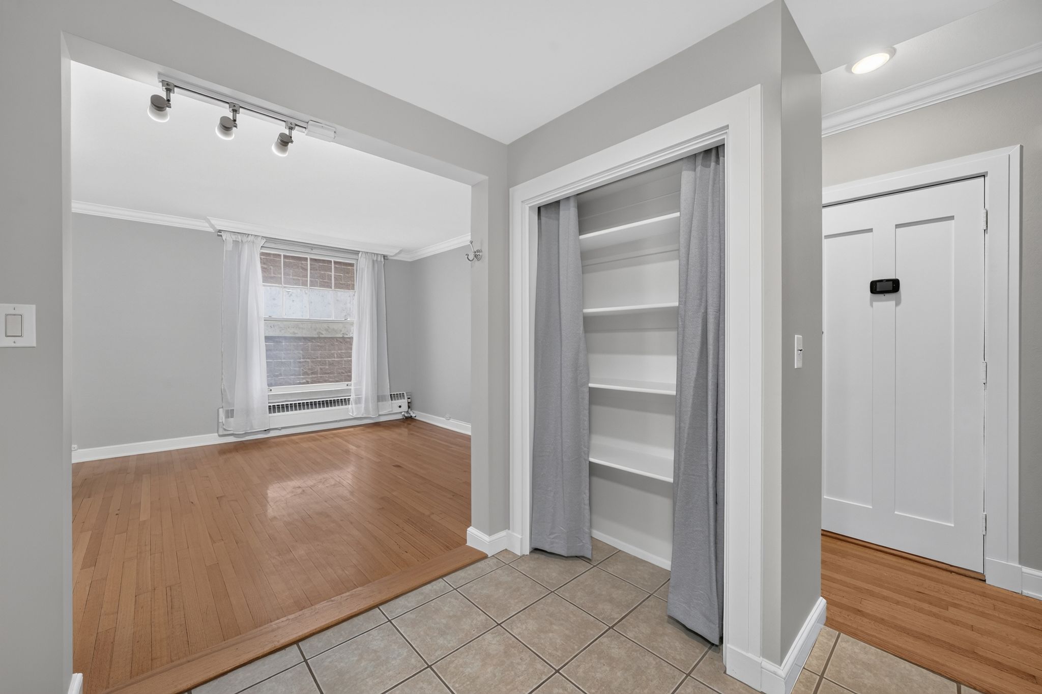 Entryway featuring ceramic tile flooring, a built-in shelving unit with curtain closure, and a paneled interior door