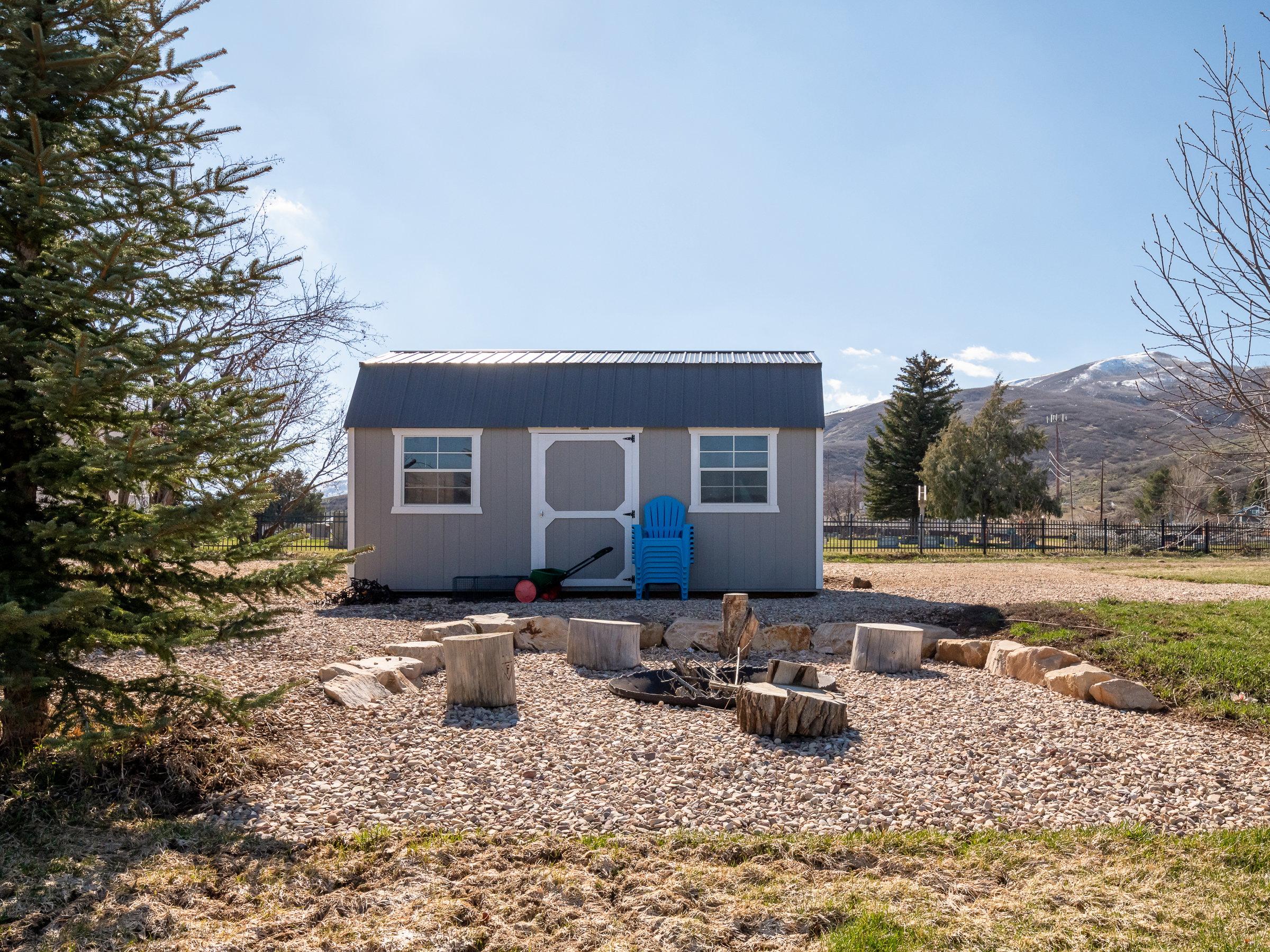 Detached storage shed featuring a corrugated metal roof and white-framed windows