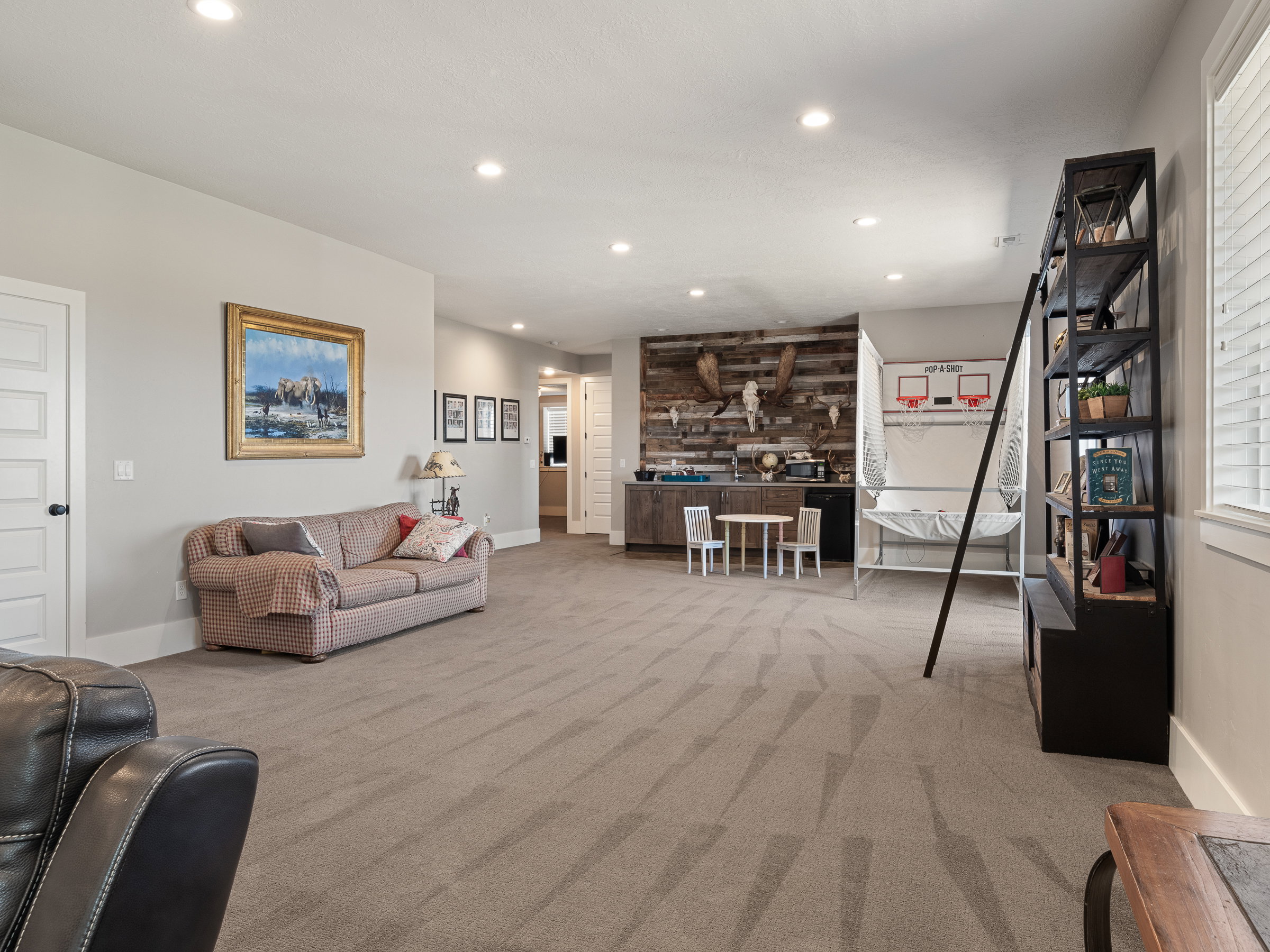 Expansive lower-level space featuring recessed lighting, plush patterned carpeting, and light gray wall finishes