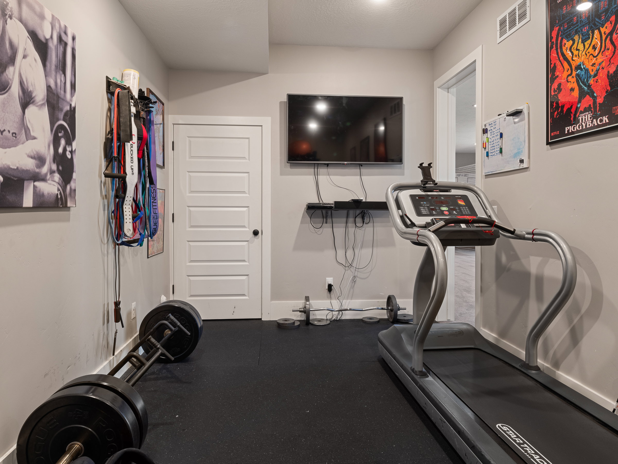 Dedicated fitness room with rubberized flooring, recessed lighting, and a wall-mounted television