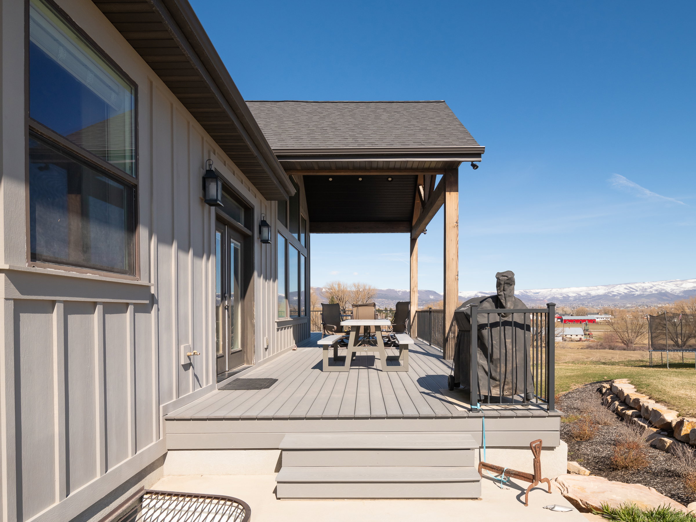 Expansive composite deck featuring a covered patio, black metal railings, and clear views of distant mountains