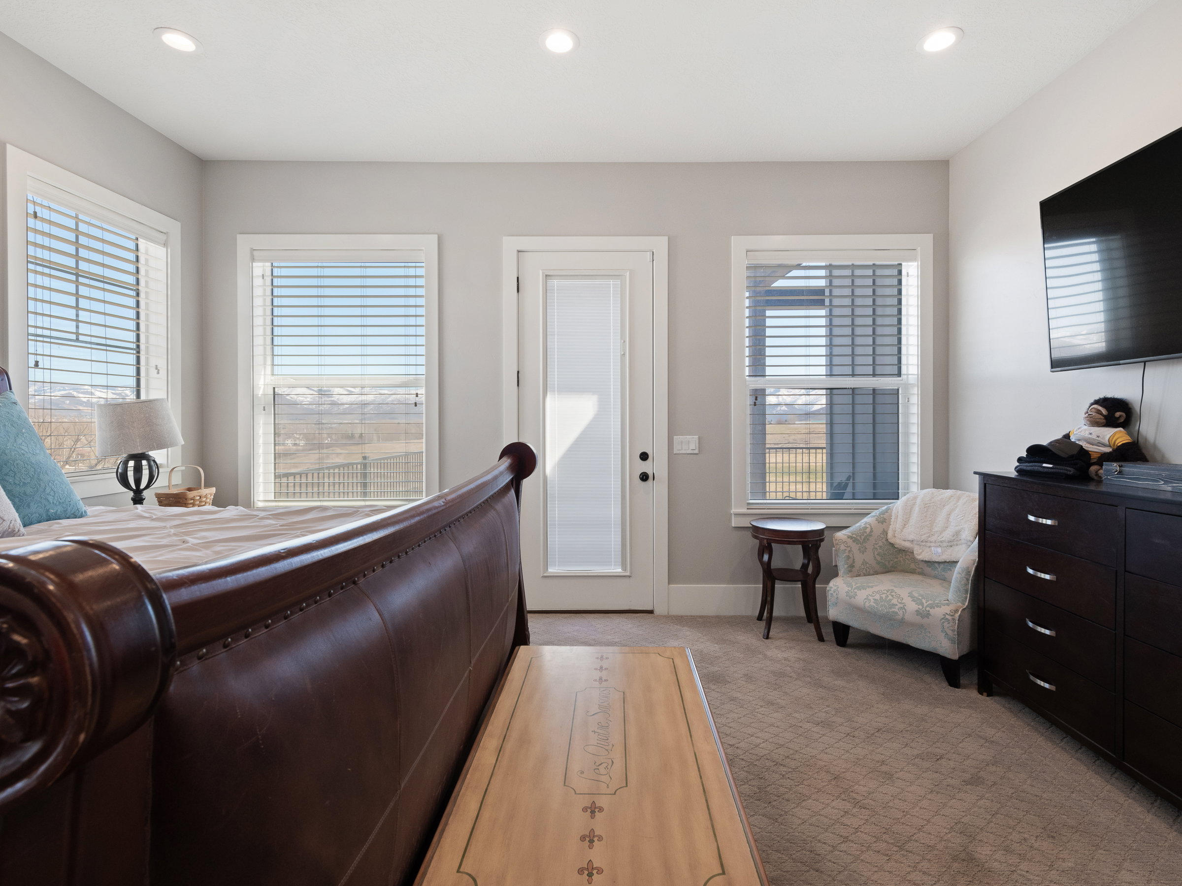 Carpeted bedroom with multiple windows, recessed lighting, and a glass-paneled door