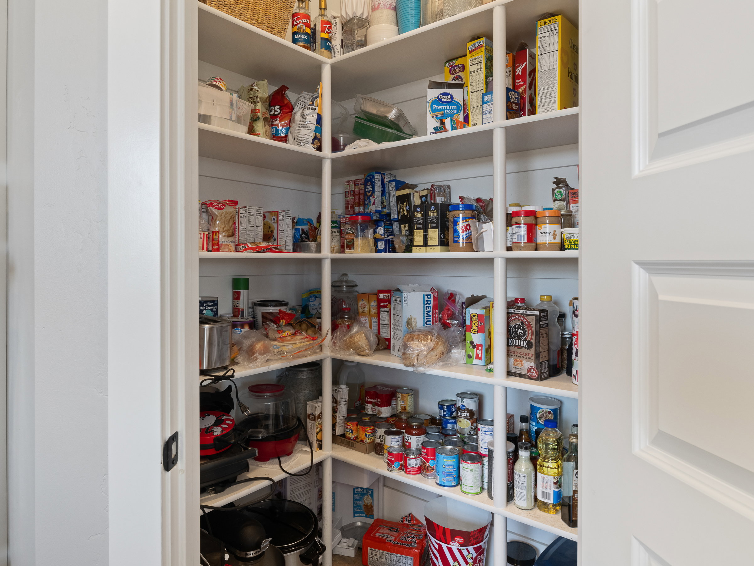 Expansive walk-in pantry featuring white shiplap walls and abundant built-in shelving for extensive storage