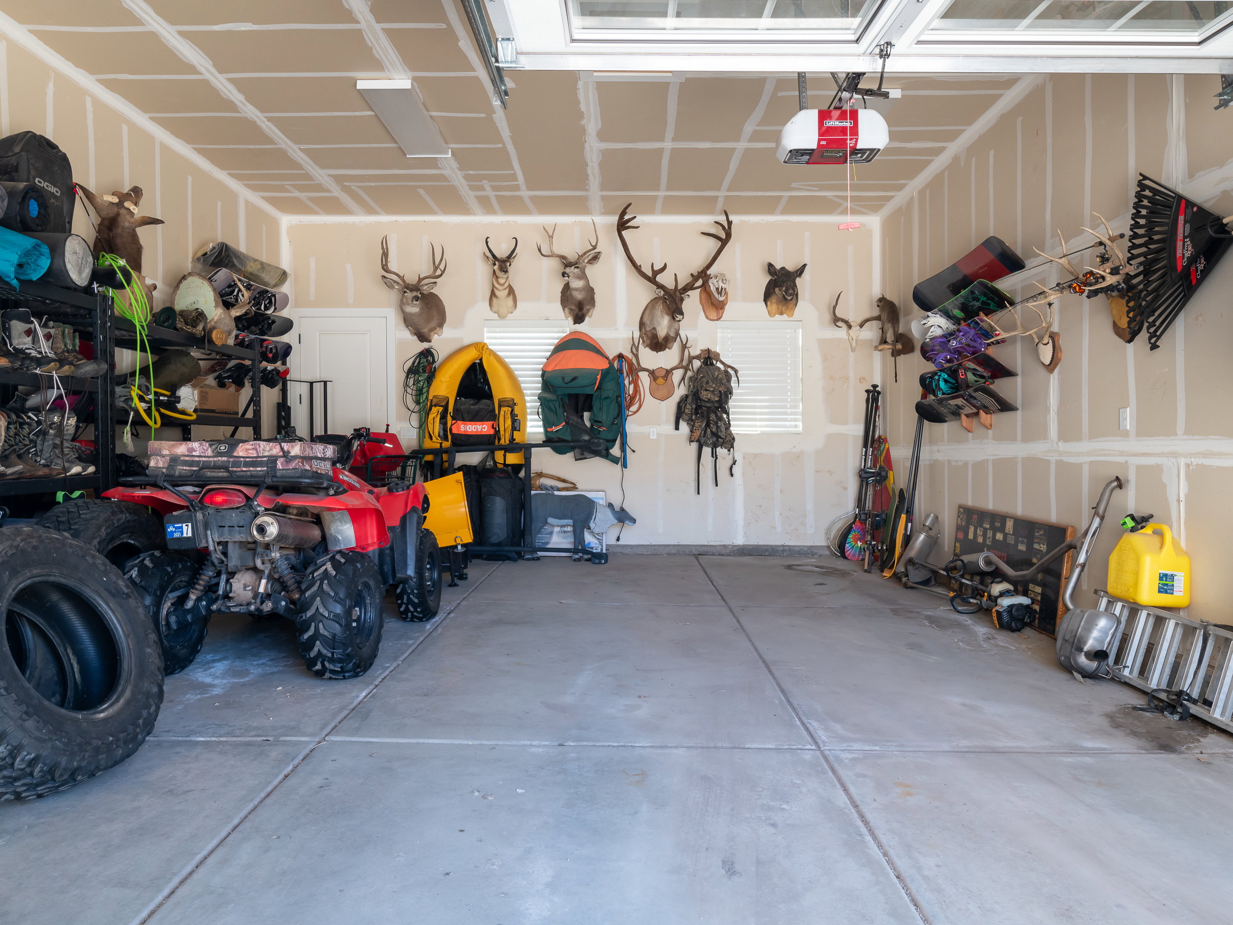 Spacious garage featuring a concrete floor, overhead garage door with opener, and a single window with blinds