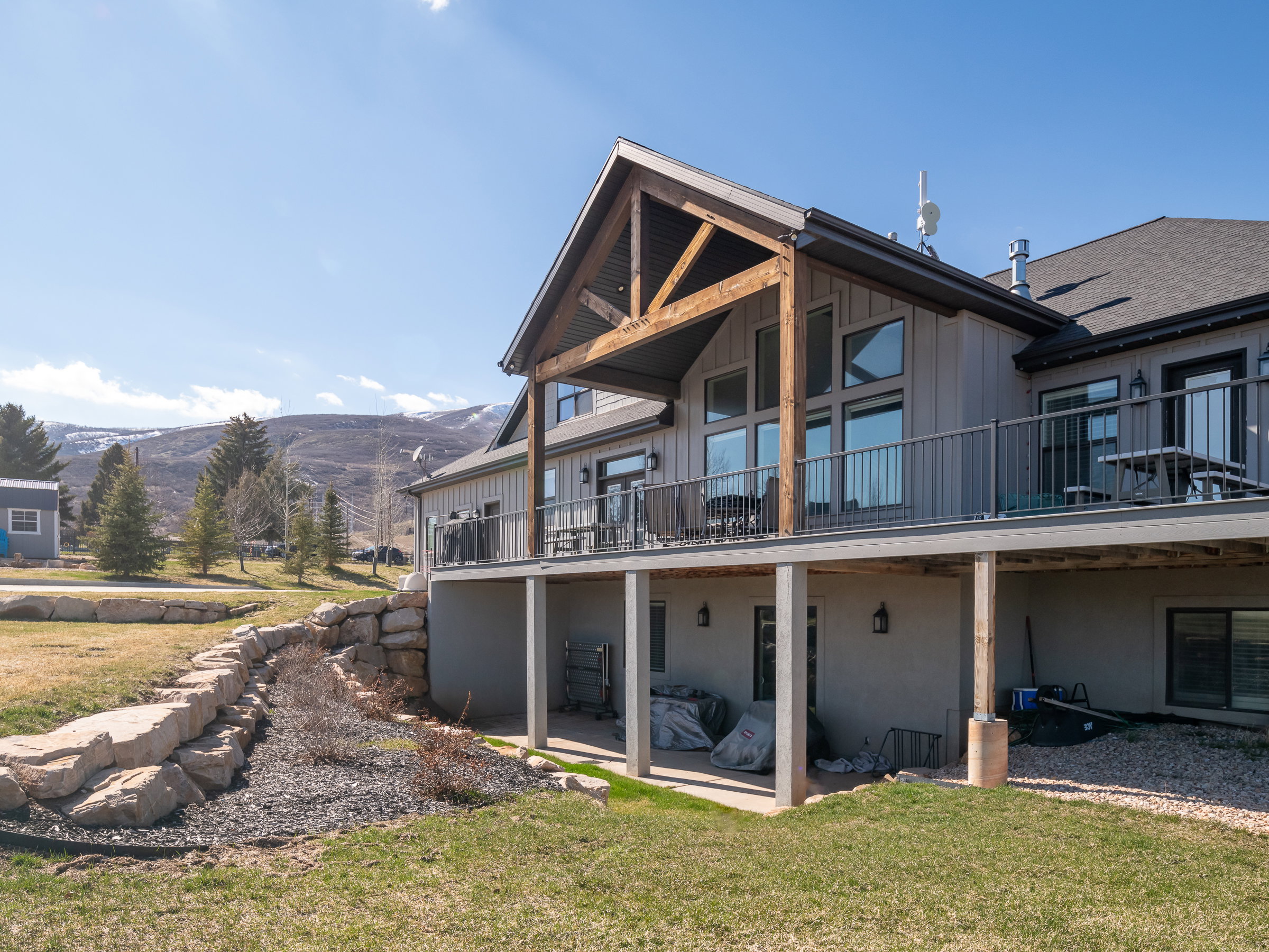 Contemporary exterior featuring a covered deck with metal railings and exposed timber framing