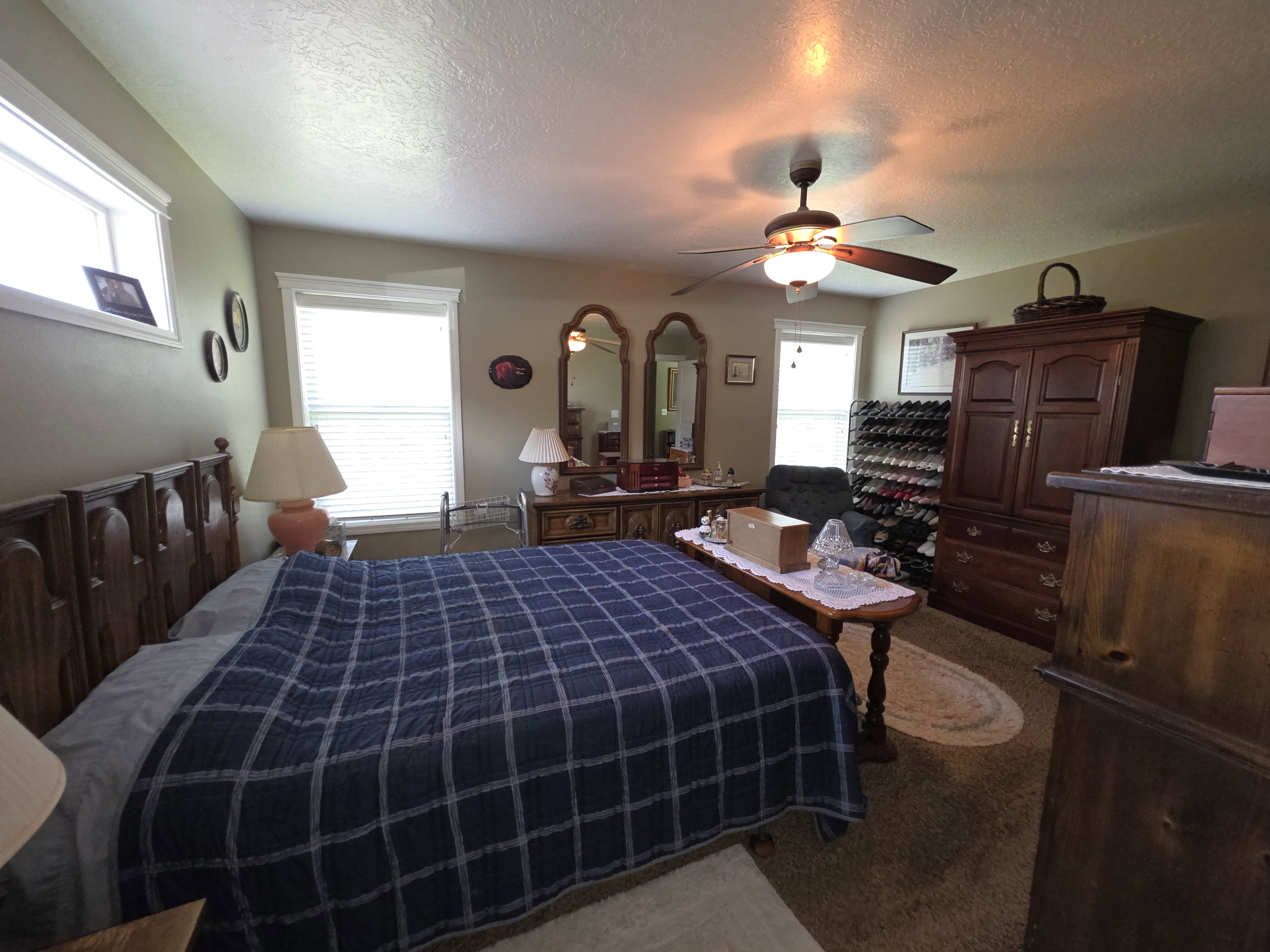 Spacious bedroom featuring multiple windows, a ceiling fan, and carpeted flooring