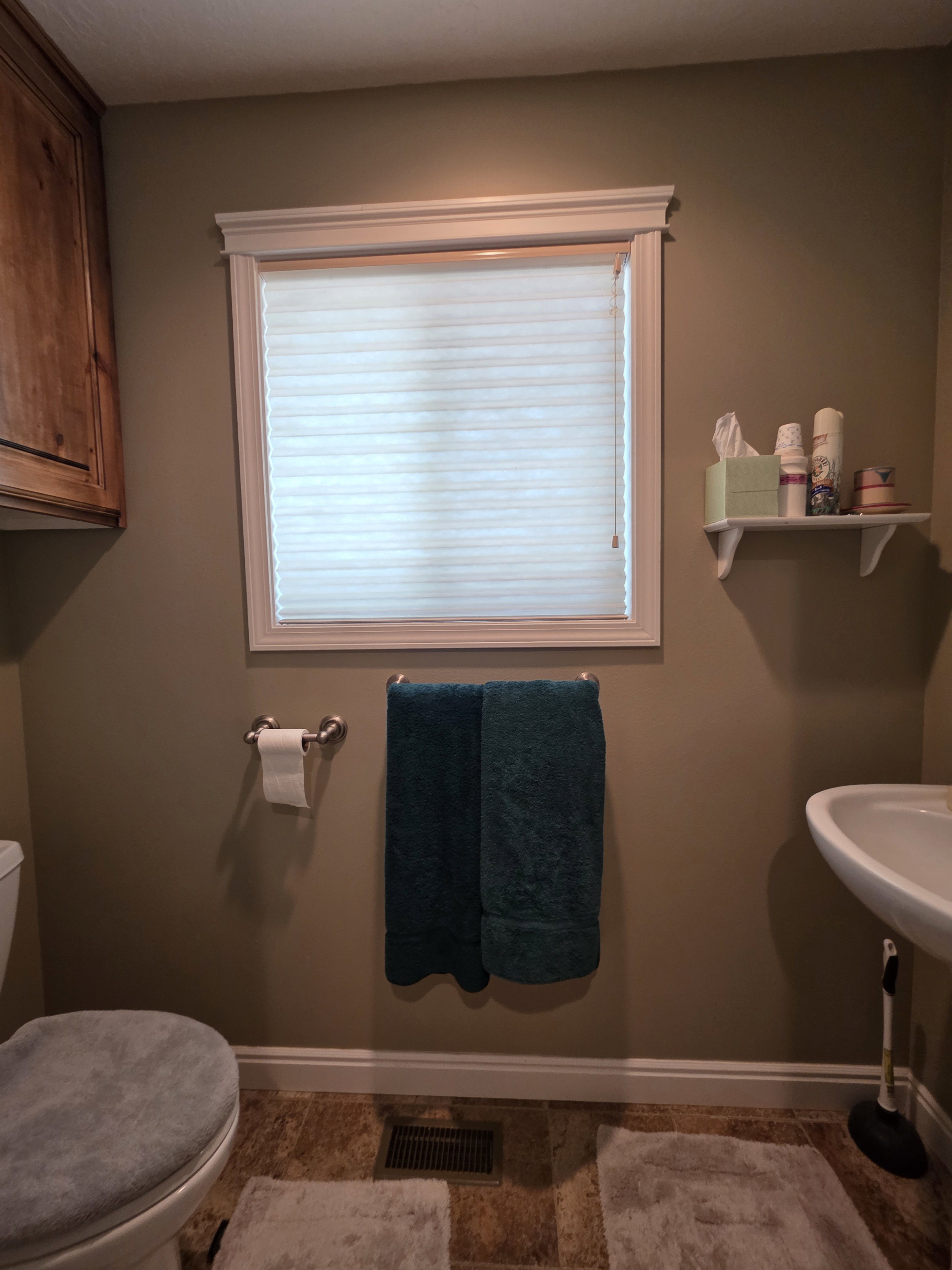 Bathroom featuring a white-trimmed window, a wall-mounted sink, built-in wooden cabinetry, and wood-finish flooring