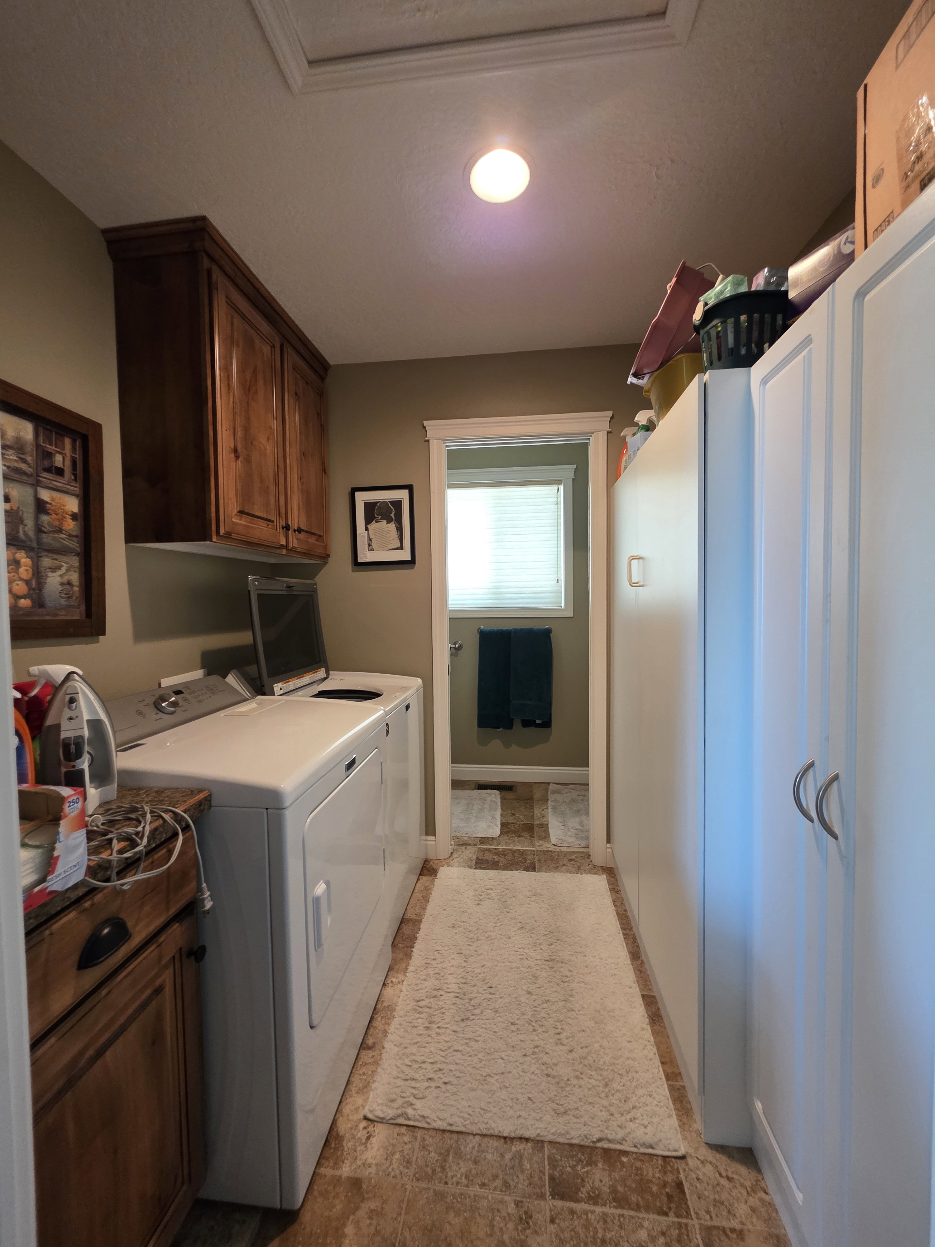 Functional utility space featuring wood-finish flooring, white built-in cabinetry with silver pulls, and additional wood cabinetry with a countertop
