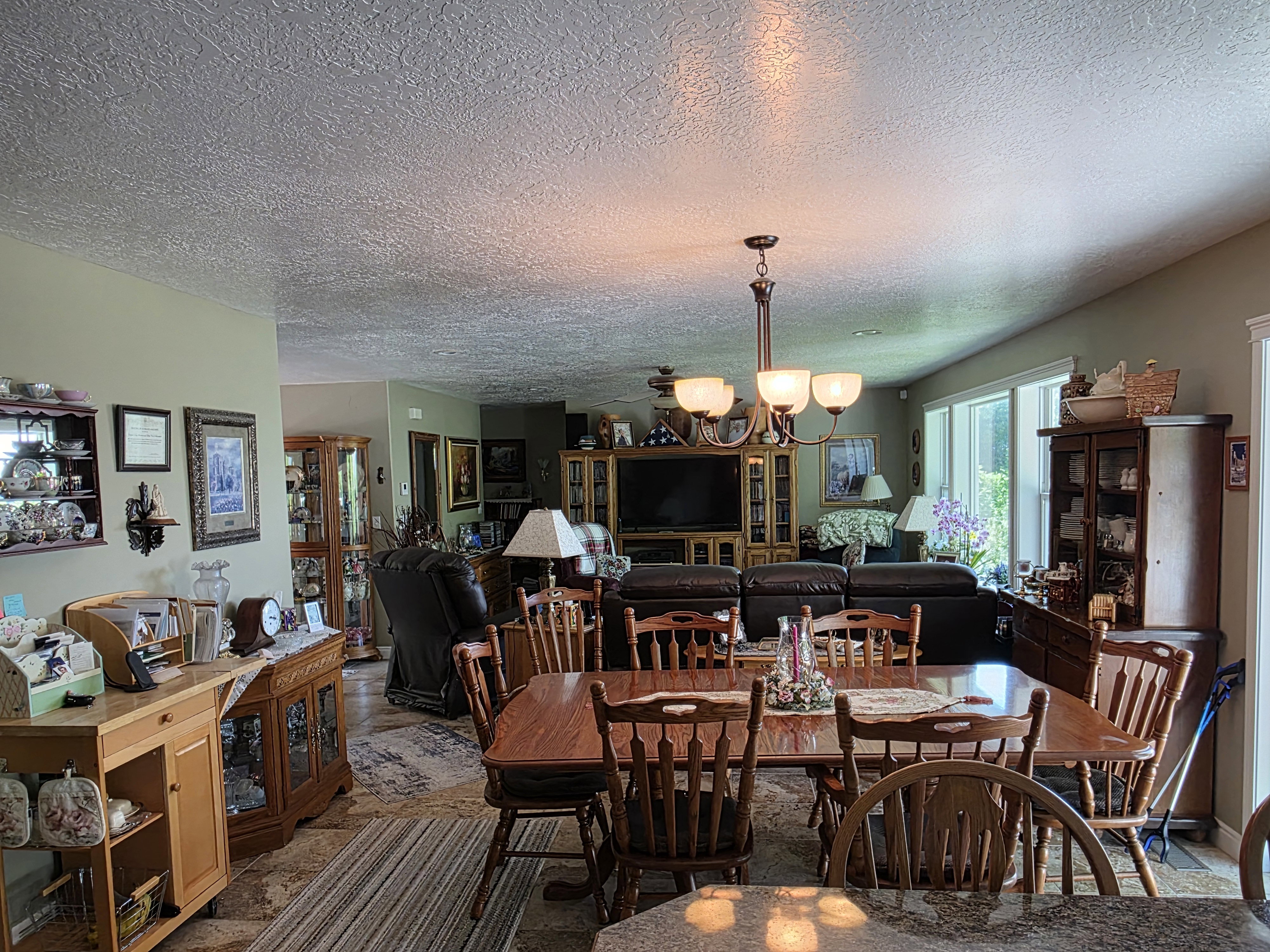 Expansive dining area with a wood-finish table, chandelier lighting, and tile flooring