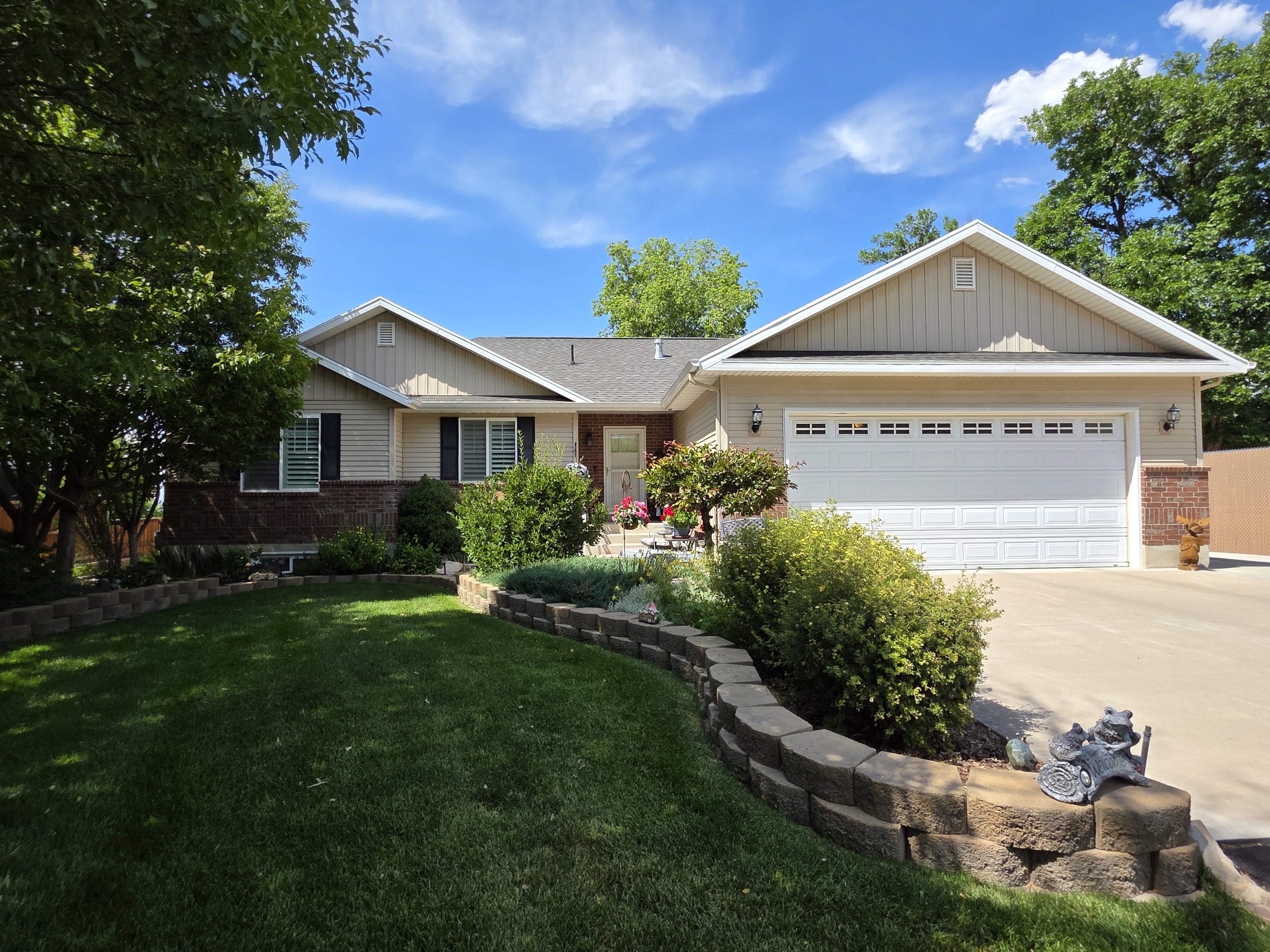 Single-story residence featuring light-colored siding, brick accents, and a two-car garage