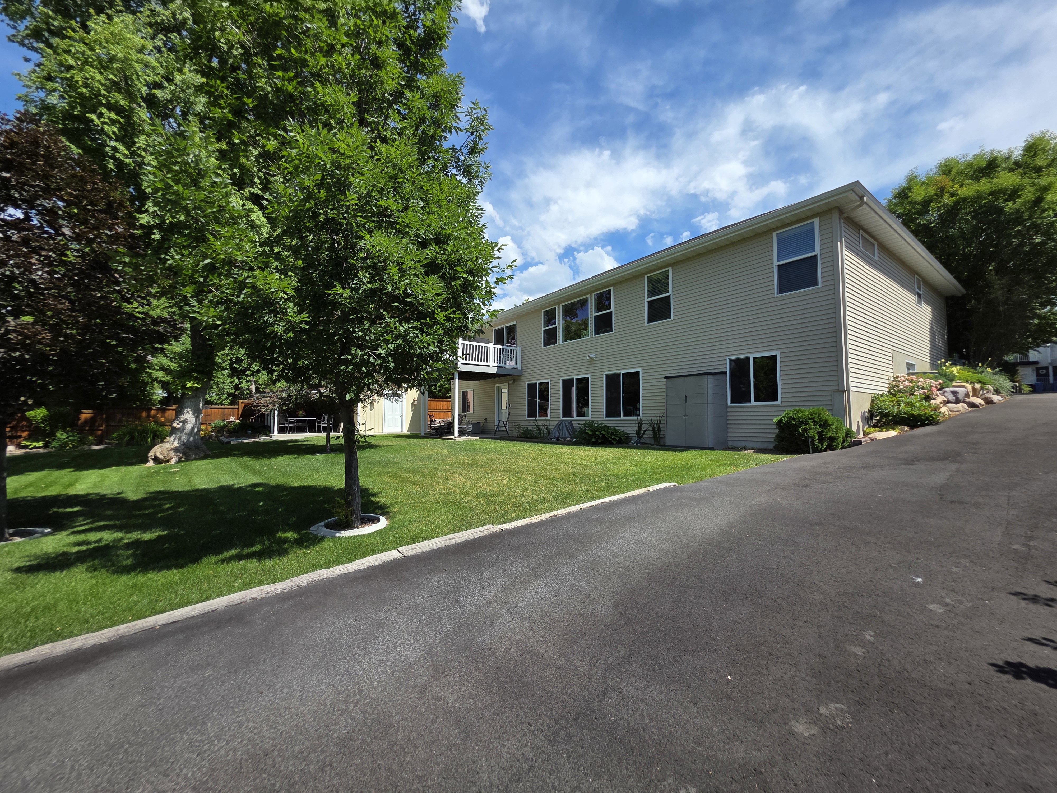 Spacious two-story residence with light-colored siding, multiple windows, and a private balcony