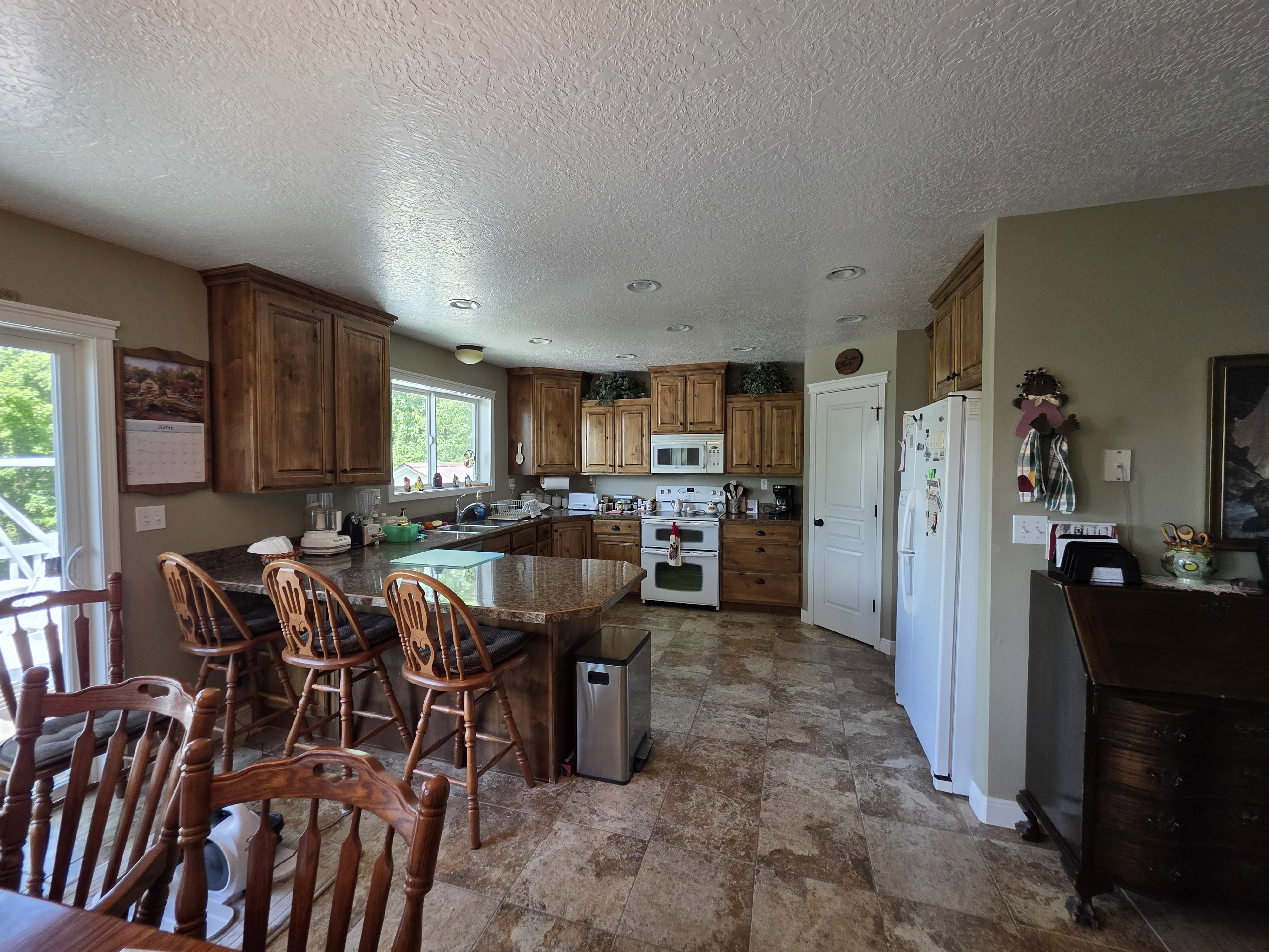 Kitchen featuring wood cabinetry, granite-style countertops, an integrated kitchen island with seating, a white electric range, and patterned floor tiling