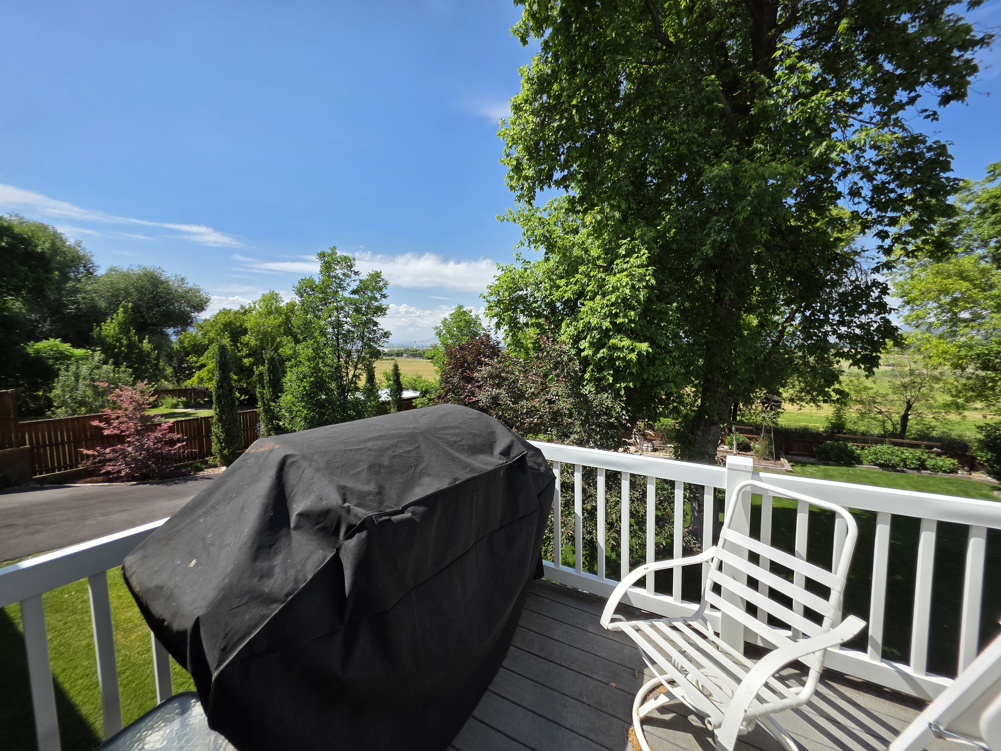 Expansive outdoor deck featuring wood-finish flooring and a white railing system