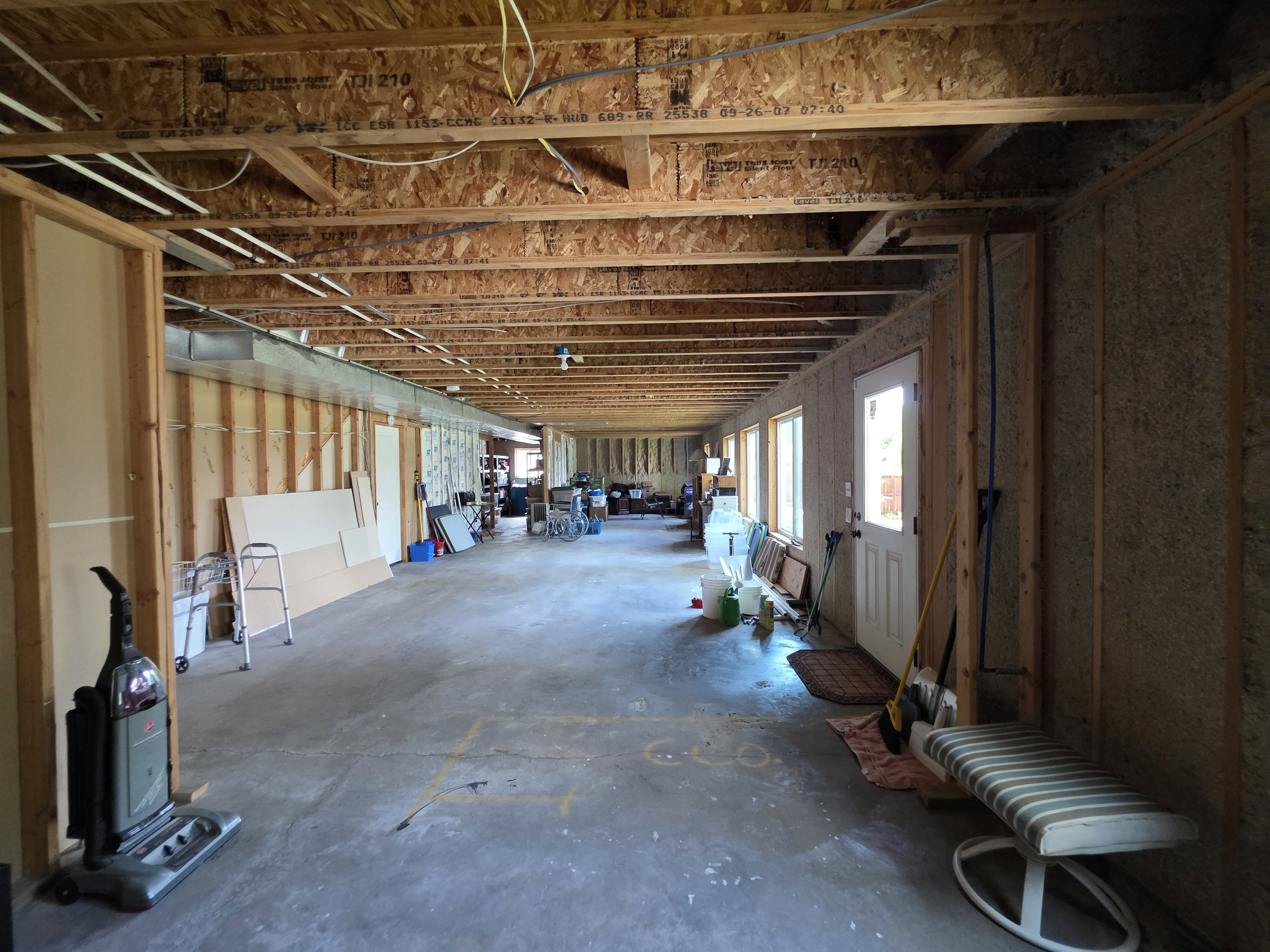 Unfinished interior space featuring exposed ceiling joists, framed wall construction, a concrete floor, and multiple windows providing natural light