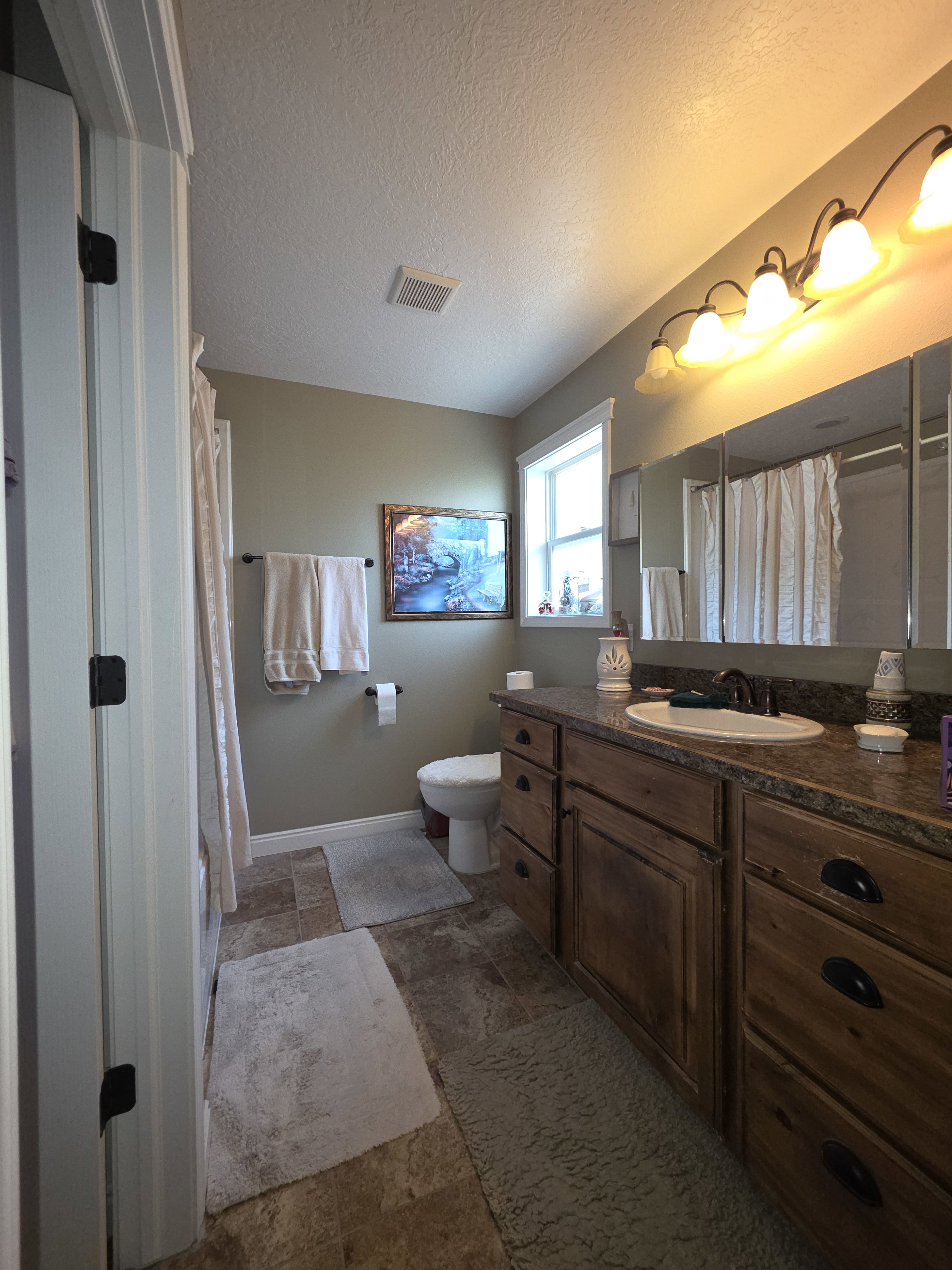 Bathroom featuring a wood vanity with a granite-style countertop and an integrated sink