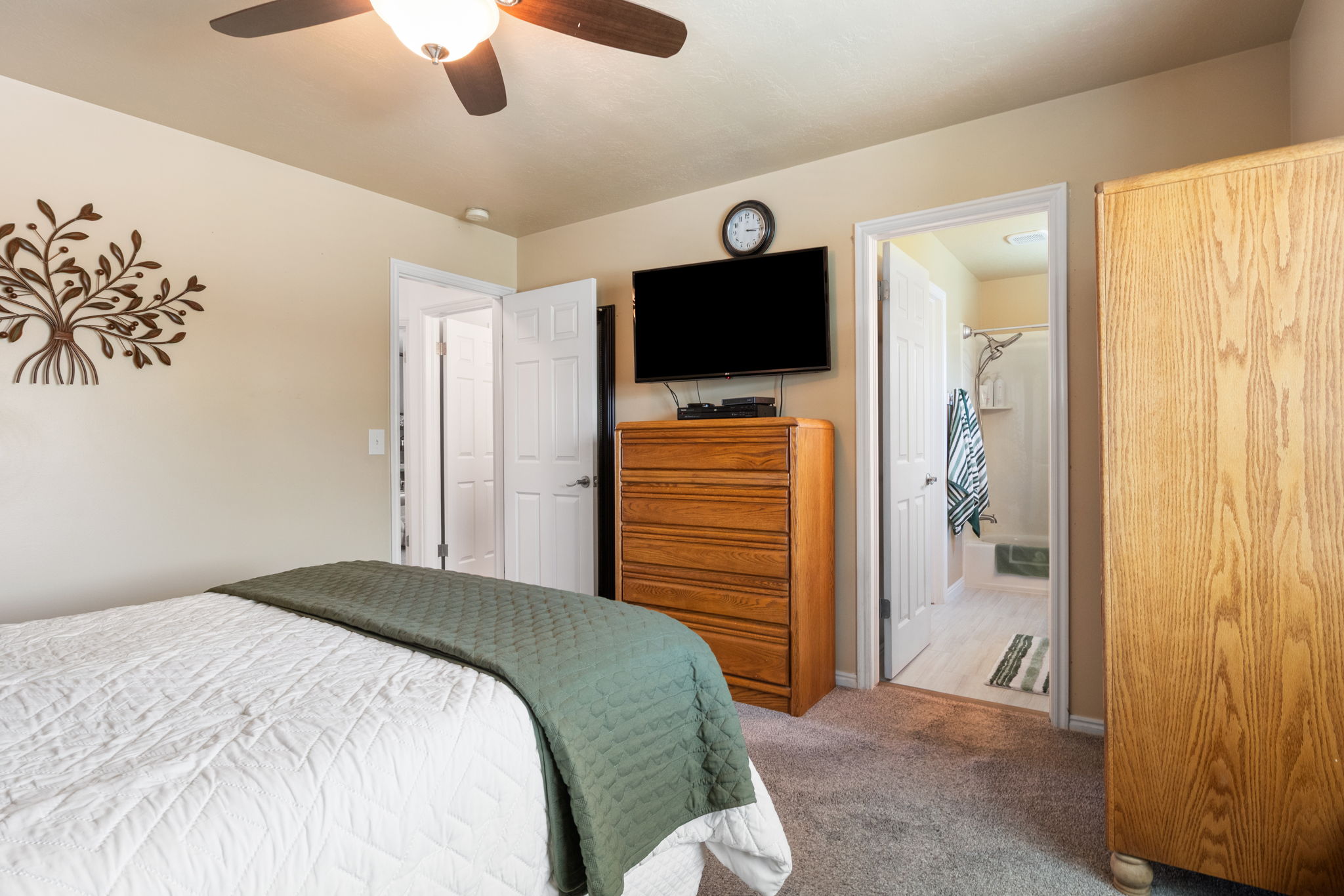 Carpeted room with a ceiling fan featuring integrated lighting, and a white paneled door
