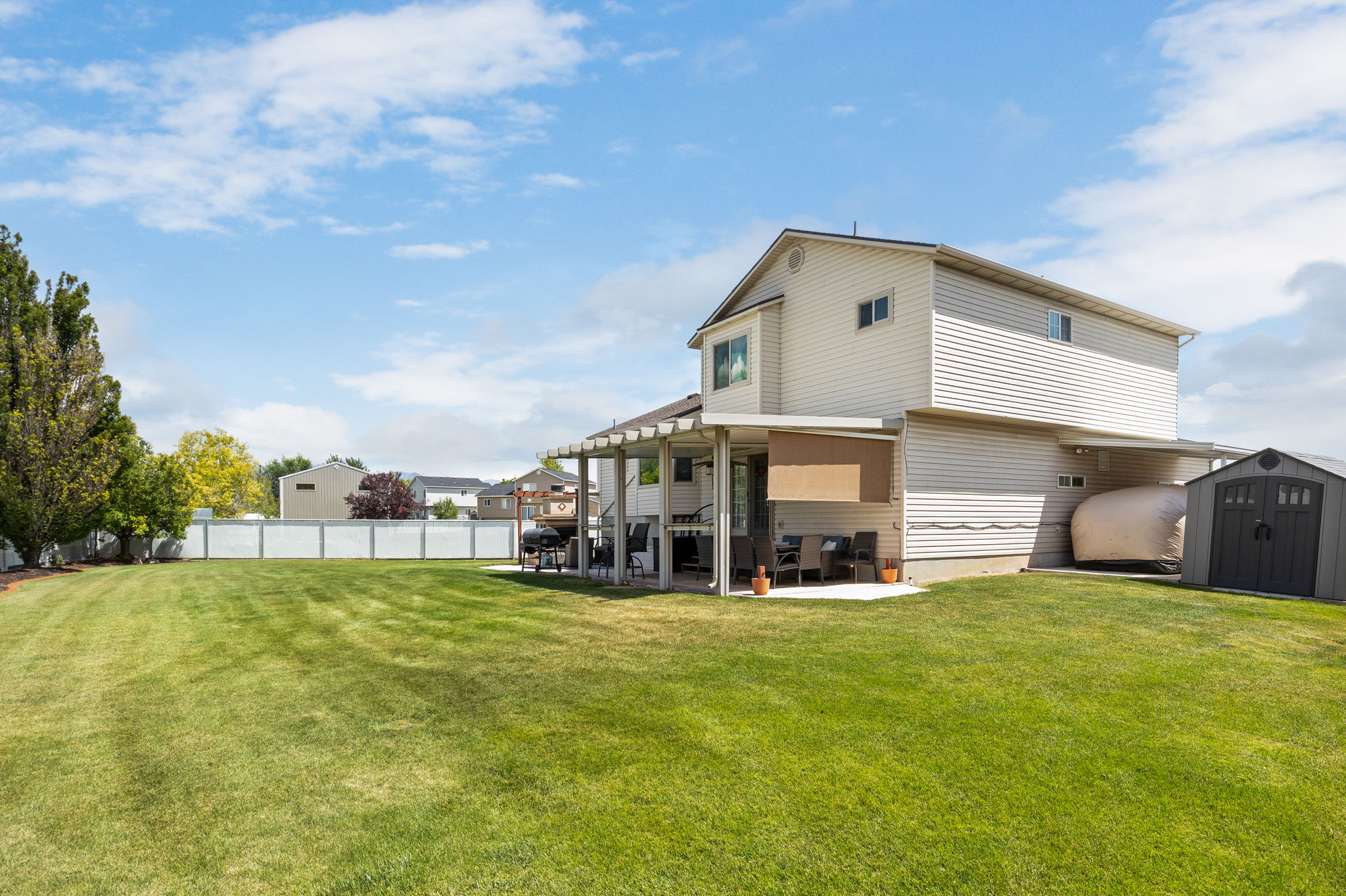 Expansive green lawn with a white privacy fence