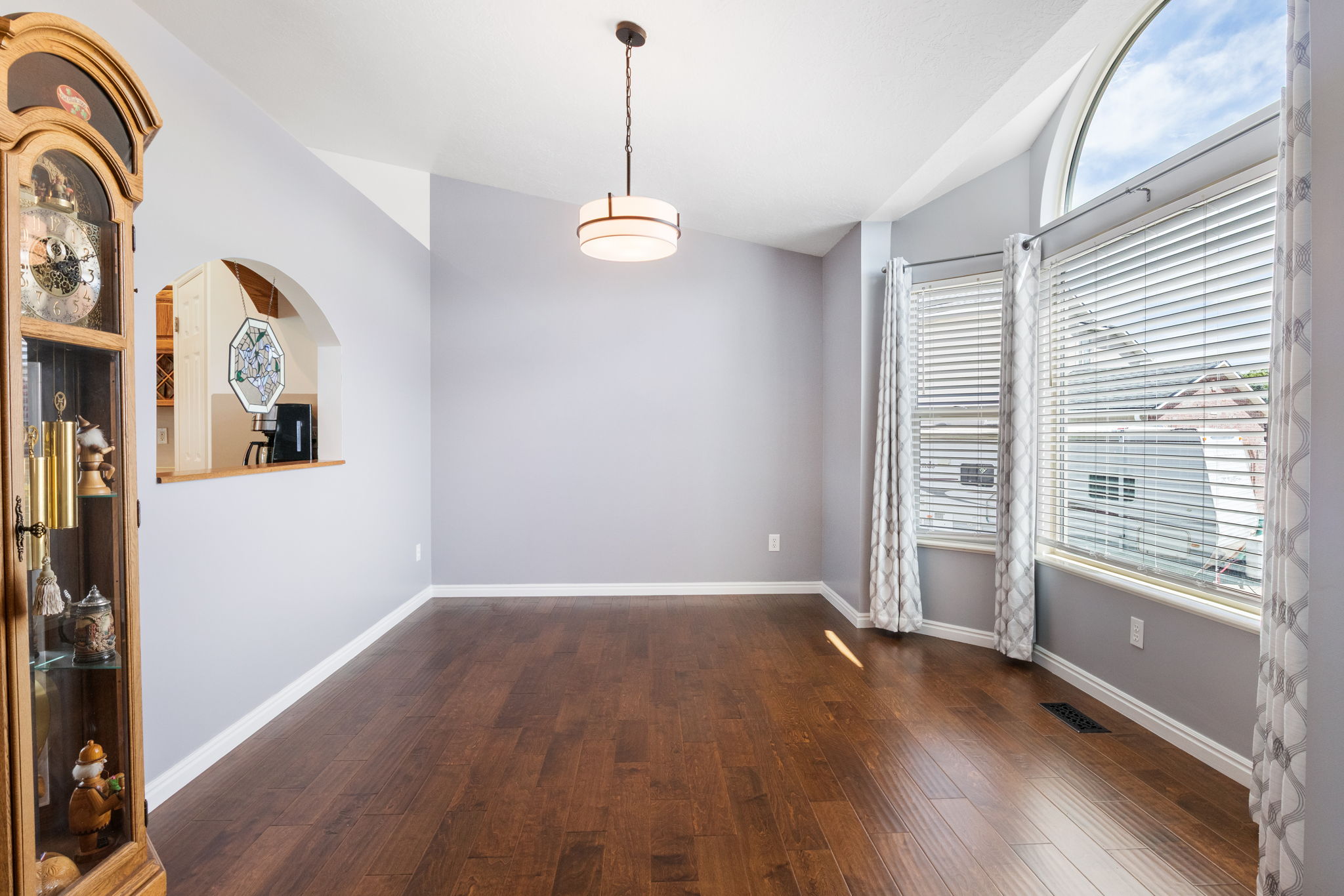 Spacious room featuring engineered wood flooring, light gray walls, and a contemporary ceiling fixture