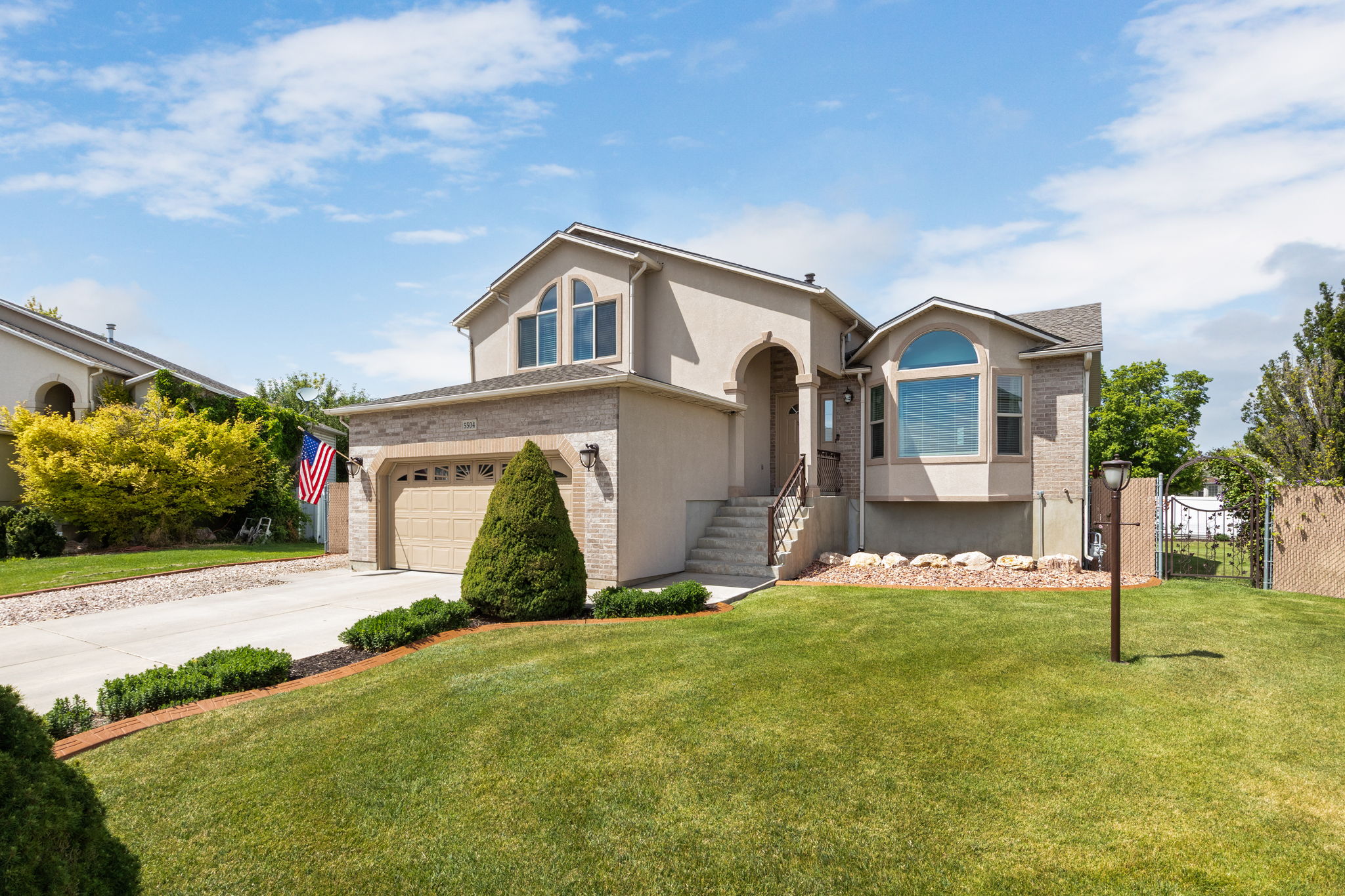Exterior featuring stucco and brick, an attached garage, arched entry, bay window, and gabled roofline