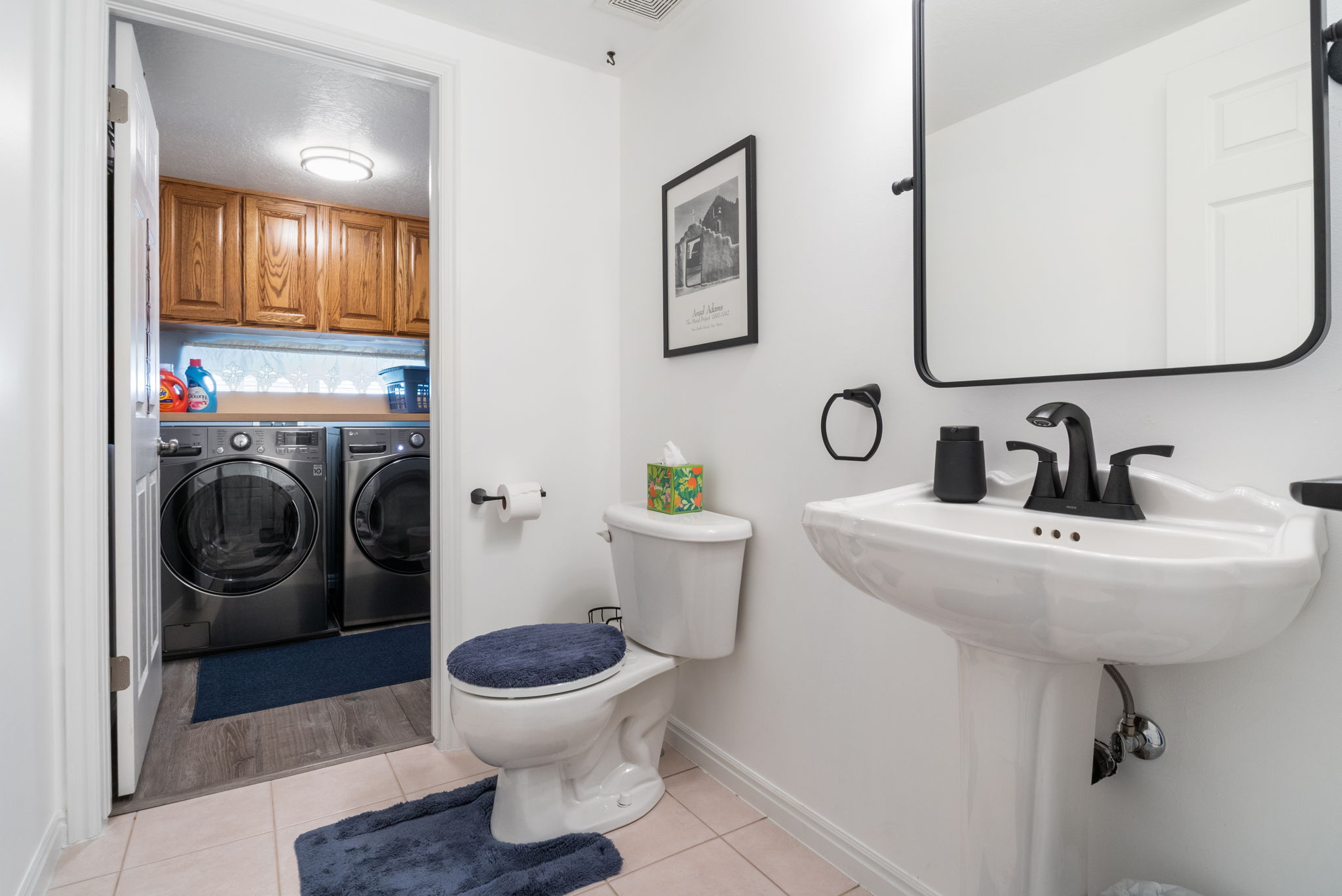 Bathroom featuring a white pedestal sink with matte black fixtures and a framed mirror
