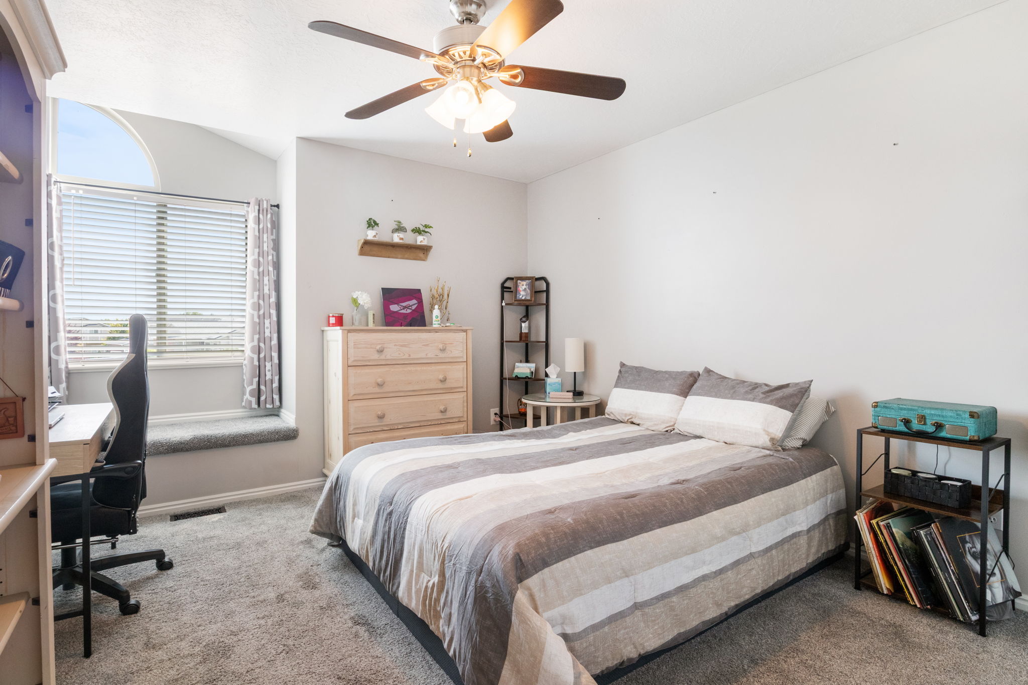 Room featuring a ceiling fan, arched transom window, horizontal blinds, and a built-in window seat