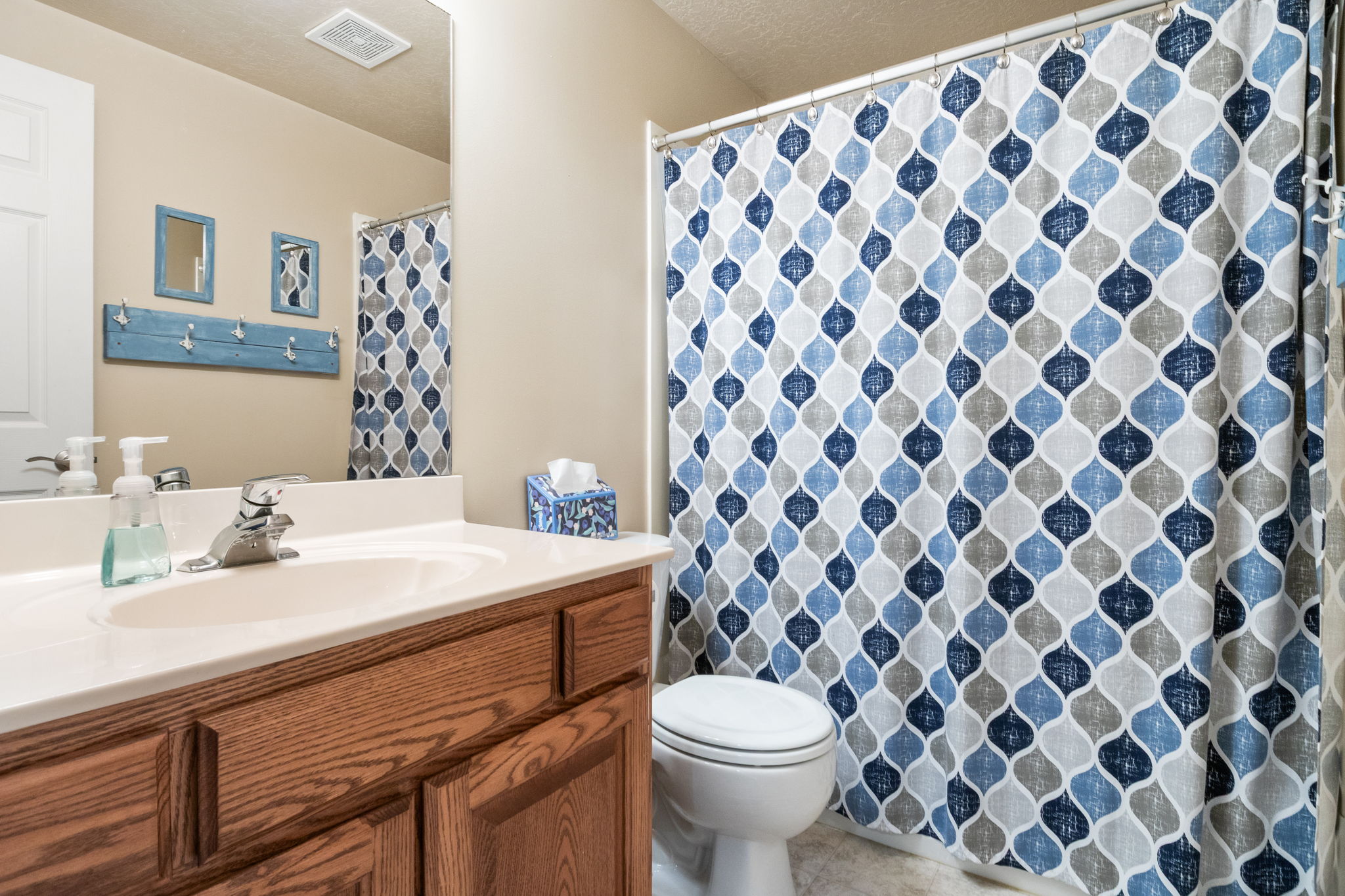 Bathroom featuring a wood-finish vanity with a white countertop and integrated sink, a large wall mirror, and a white toilet