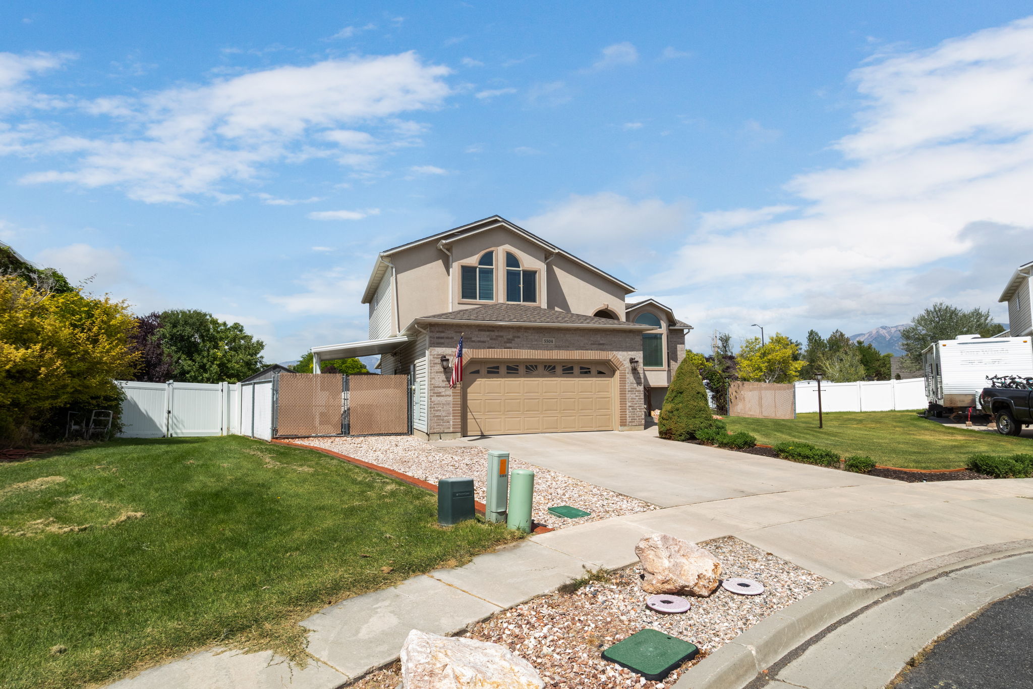Residence featuring an attached two-car garage, concrete driveway, and white privacy fencing