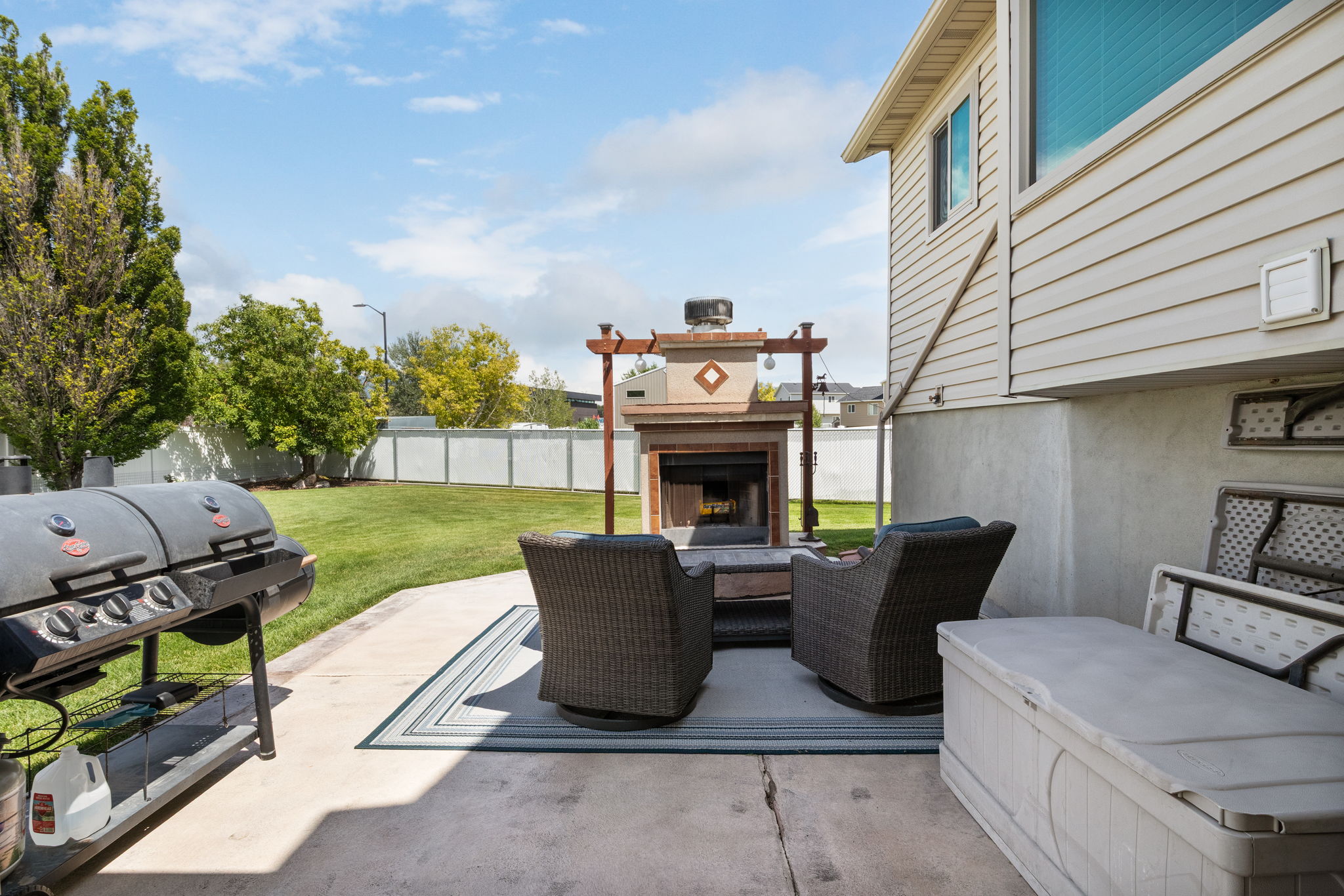 Expansive patio featuring a built-in outdoor fireplace, concrete pad, and a manicured lawn