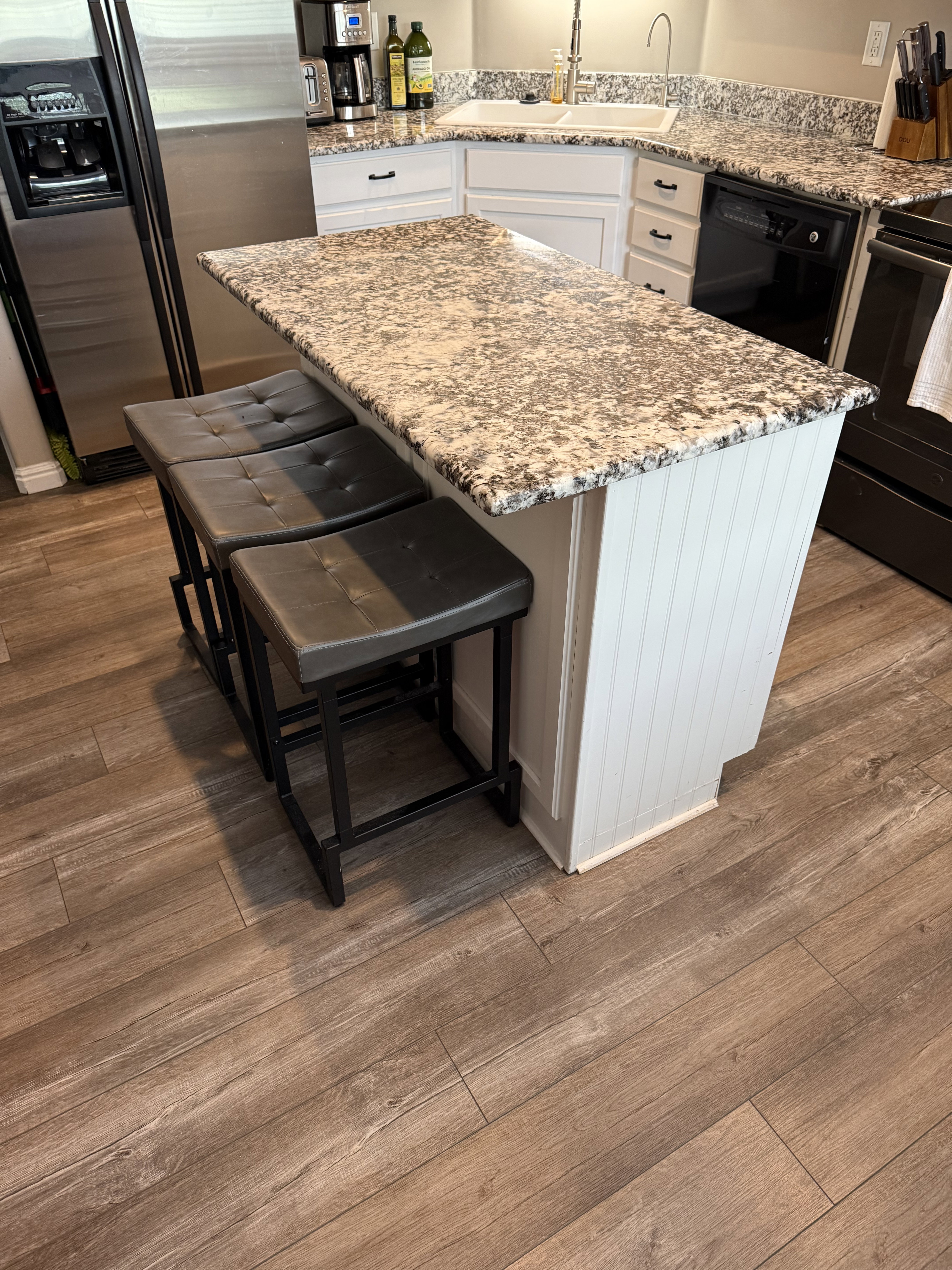 Kitchen island featuring a patterned countertop and white beadboard paneling