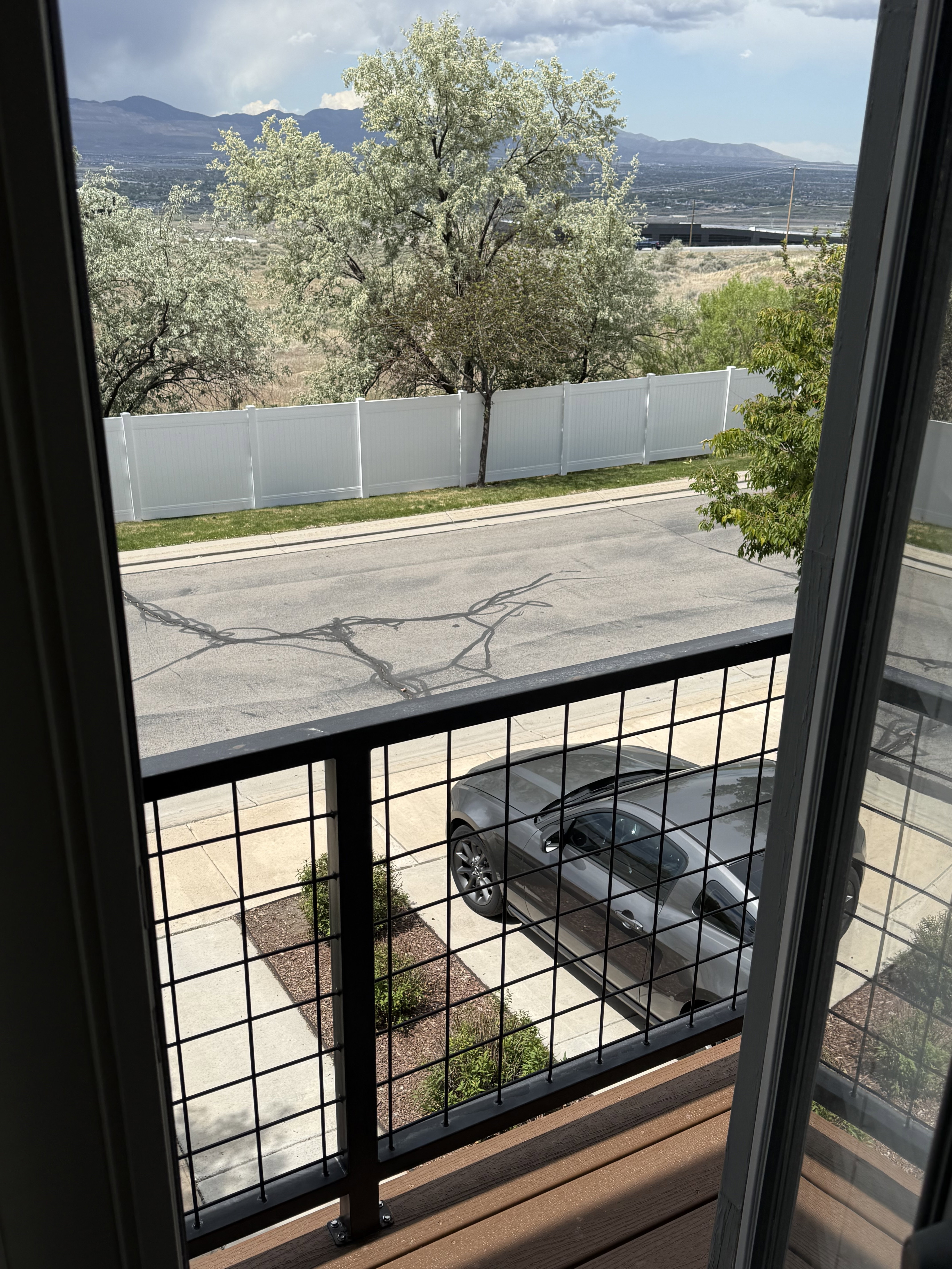 Private balcony with a dark wood-finish deck and black metal grid railing